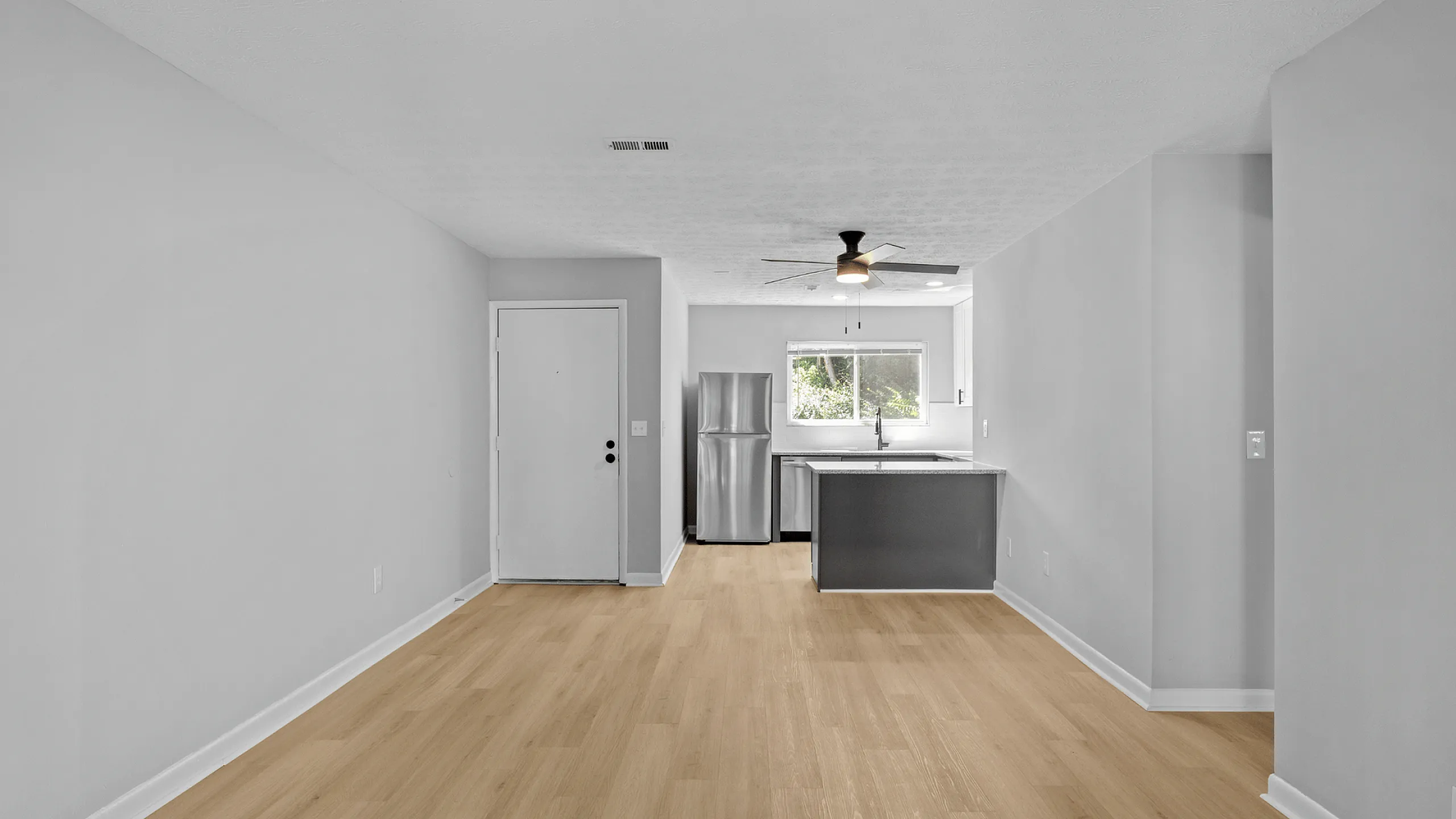 Modern open-concept kitchen with stainless steel appliances and natural light in a stylish apartment.