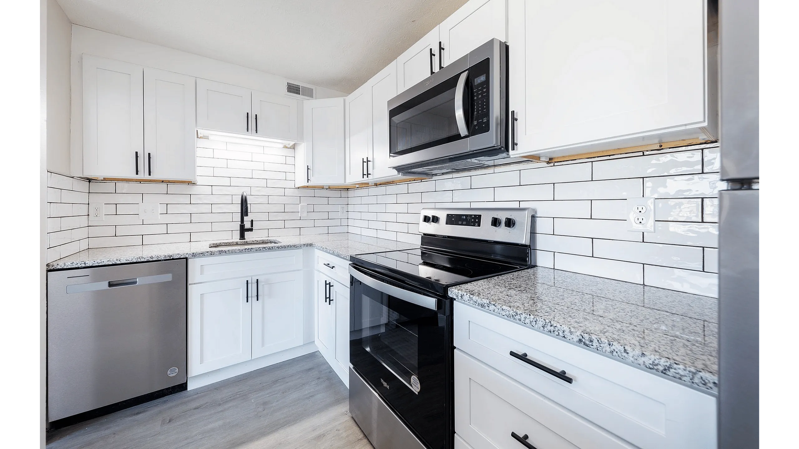 Fairfield Square Apartments Renovated Kitchen, aModern kitchen with sleek stainless steel appliances, elegant white cabinets, and a stylish subway tile backsplash.