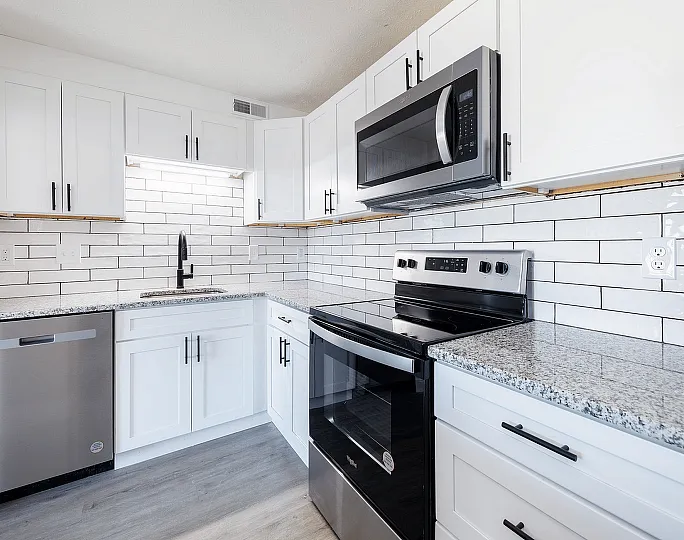 Fairfield Square Apartments Renovated Kitchen, aModern kitchen with sleek stainless steel appliances, white cabinetry, and elegant granite countertops.