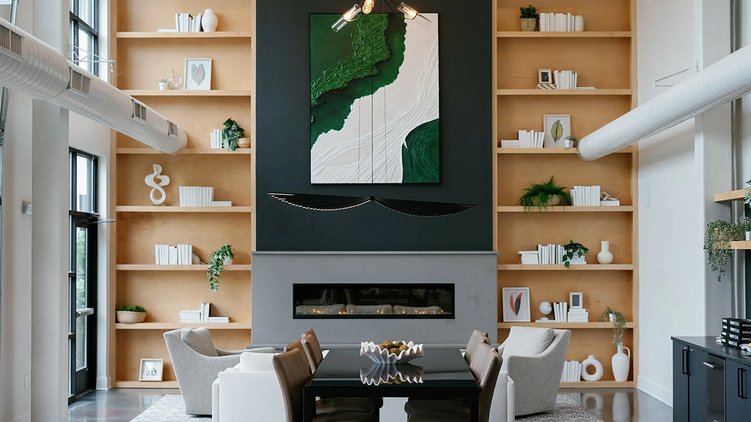 Modern living space with high ceilings, elegant shelving, art centerpiece, chic fireplace, and stylish dining area. The Ave apartments in Columbus OH, apartments in Clintonville, clintonville apartments, apartments in columbus ohio, one bed