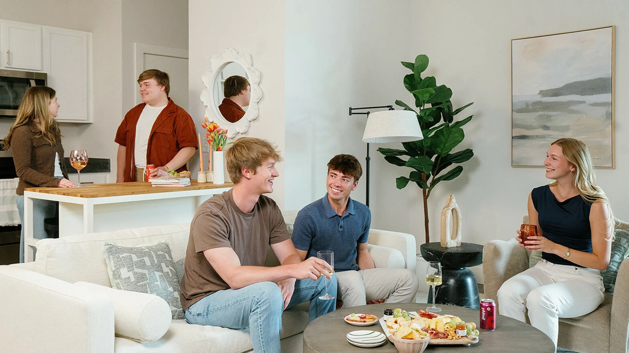 Vibrant living room with friends enjoying snacks and drinks in a modern, cozy apartment setting. The Ave apartments in Clintonville, The Ave apartments in columbus ohio, columbus ohio apartments, one bedroom apartments Columbus