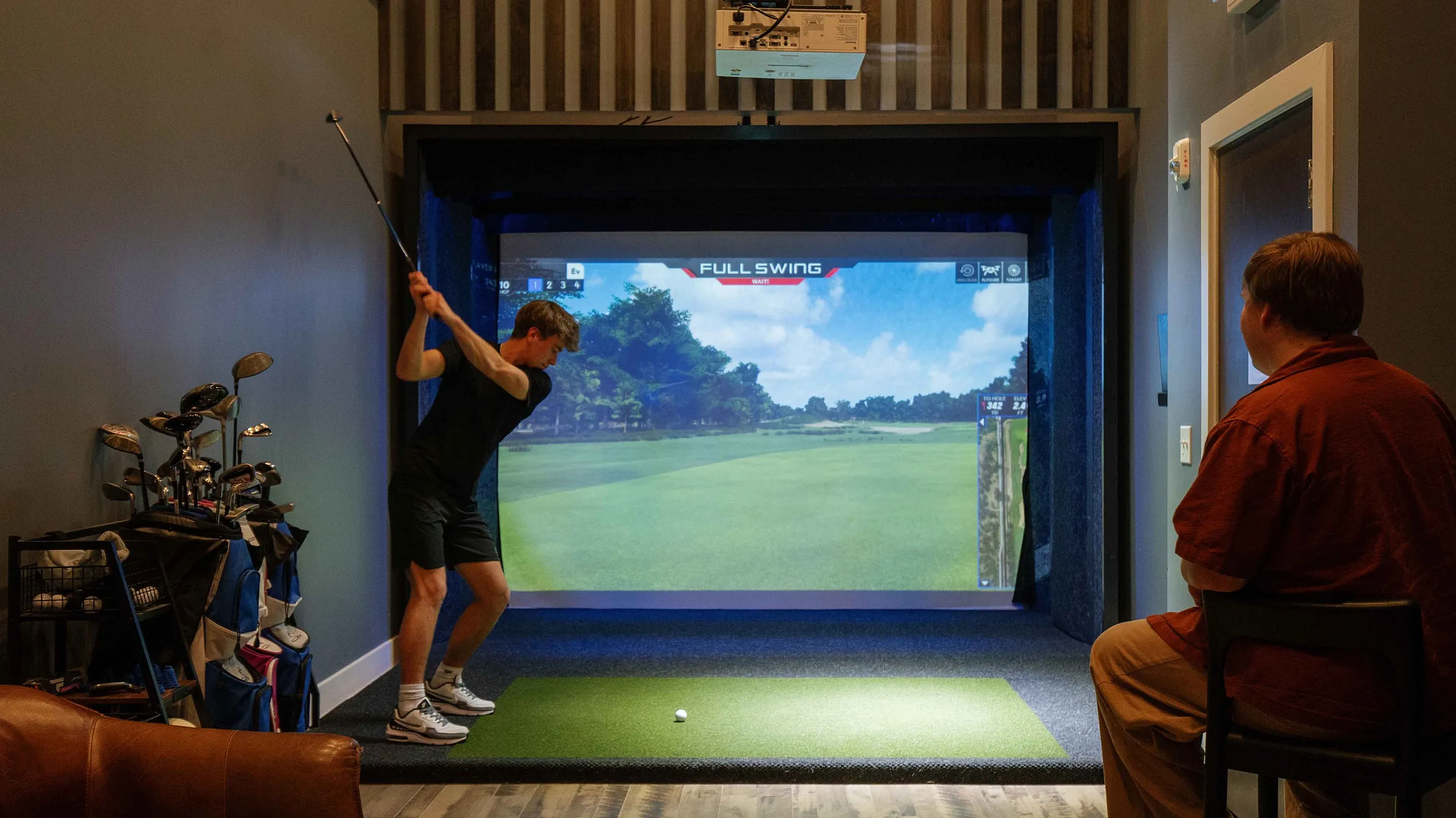 Resident sports simulator room at The Ave Apartments in Clintonville, Columbus, OH featuring a Full Swing golf simulator for year-round recreation.