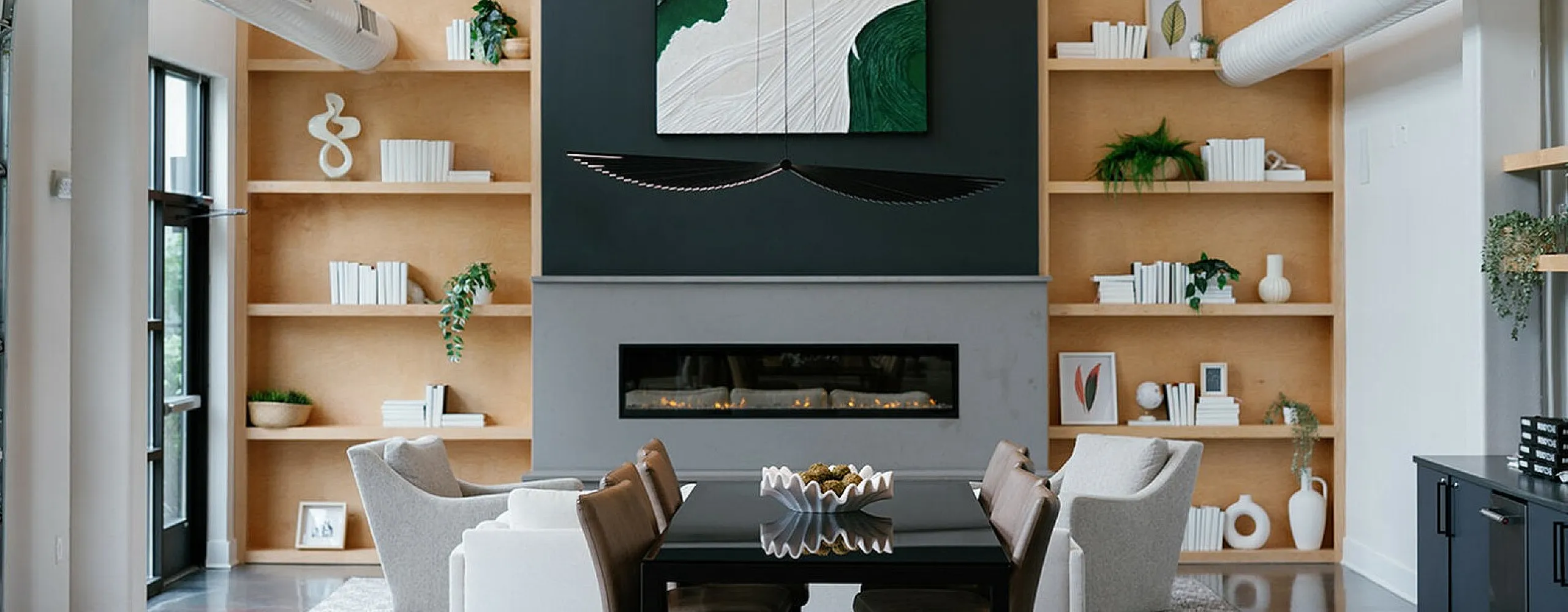 Modern living room with high ceilings, stylish bookshelf display, chic artwork, and a cozy fireplace for an inviting atmosphere.