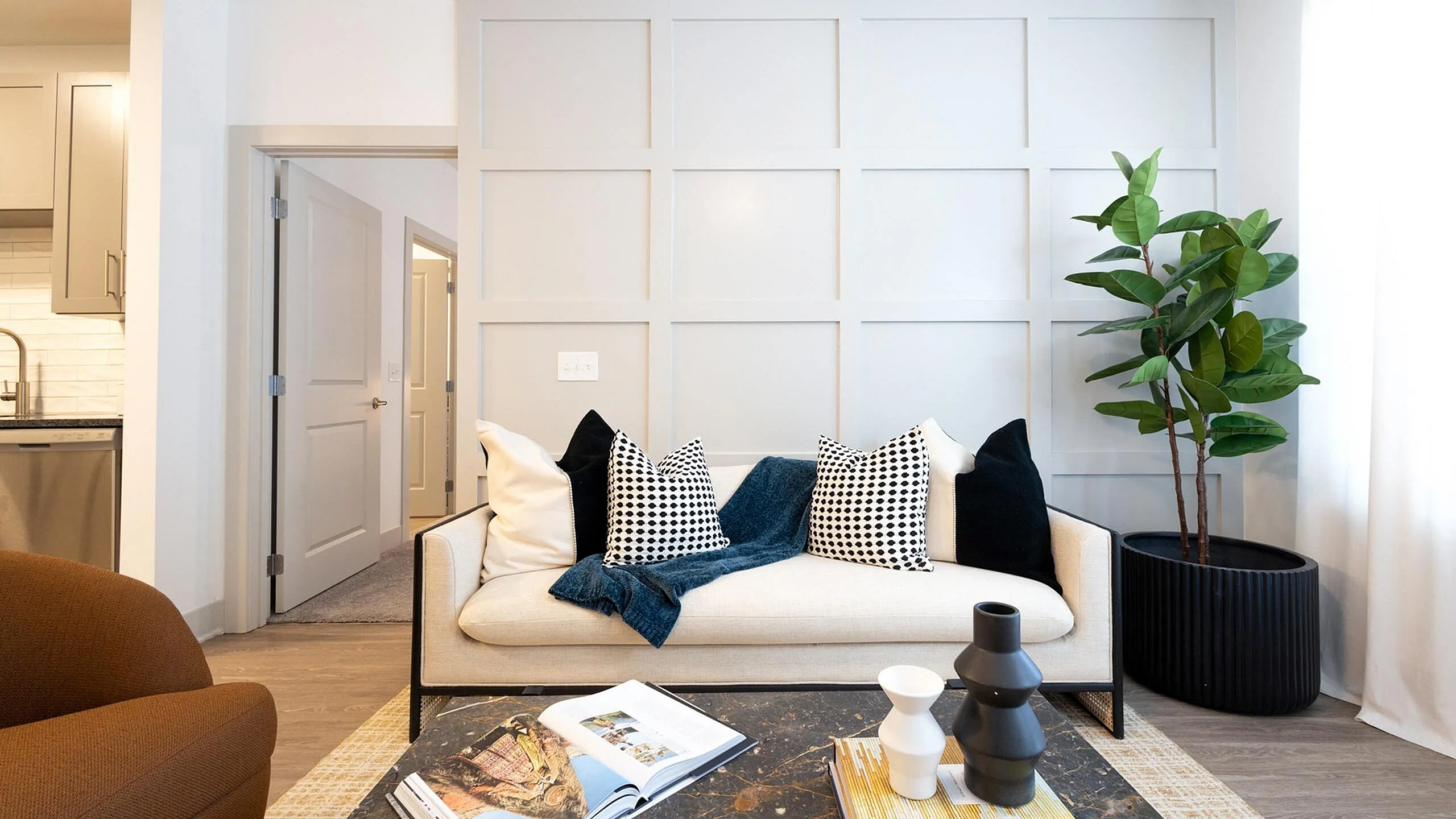 Chic living room with elegant sofa, vibrant green plant, and artistic decor in a modern apartment.