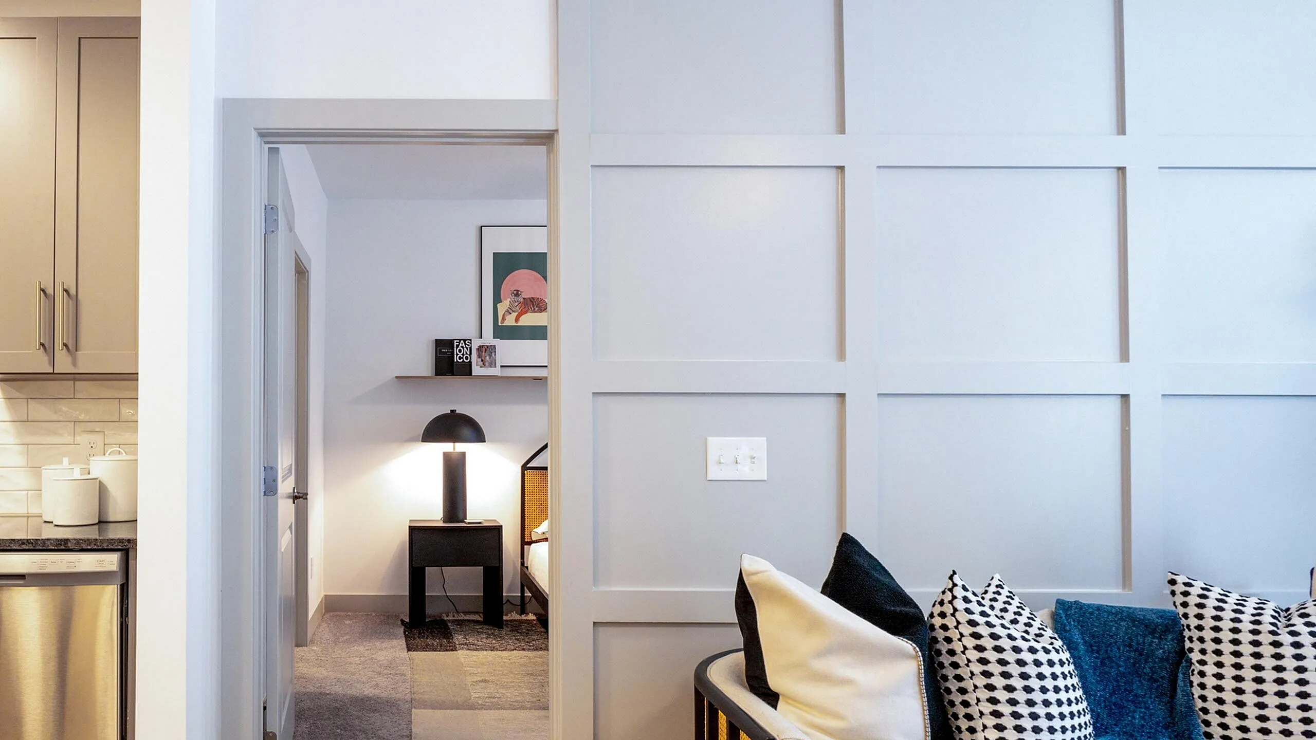 Chic modern apartment featuring elegant panel walls, cozy bedroom with stylish decor, and a sleek kitchen with stainless steel appliances.