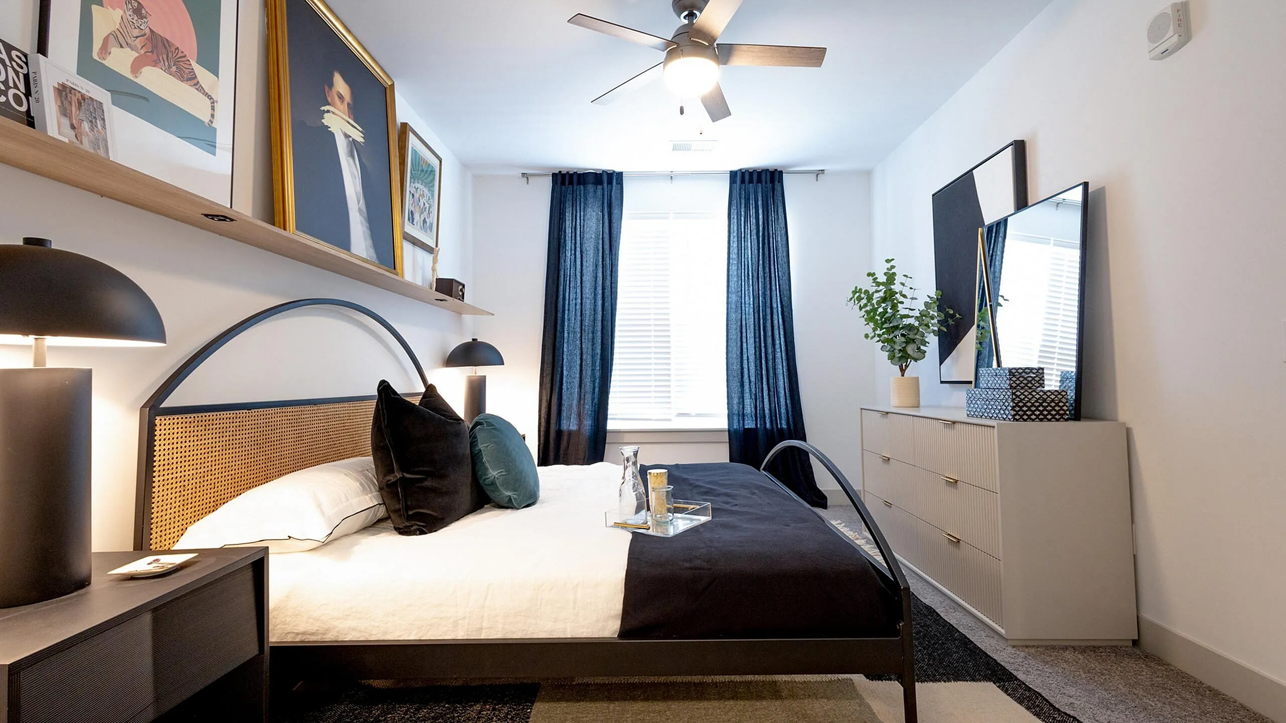 Elegant bedroom featuring a stylish framed artwork, cozy reading lamps, and chic decor with modern black and wood accents.