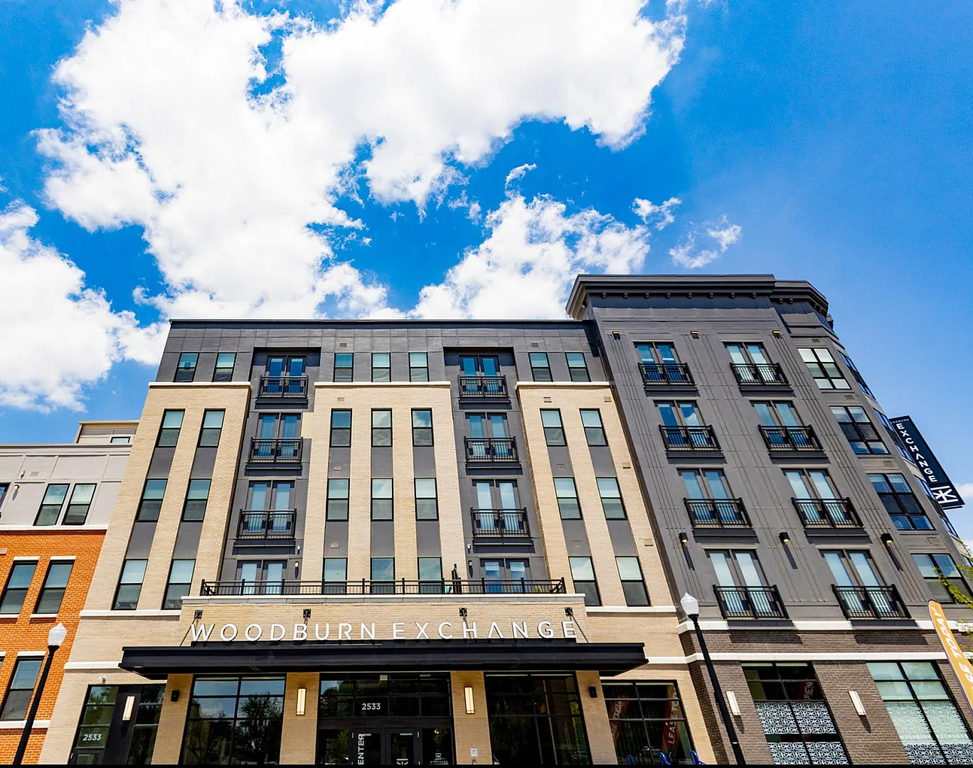 Impressive modern apartment building under a vibrant blue sky, showcasing contemporary architectural design with balconies and chic facade.