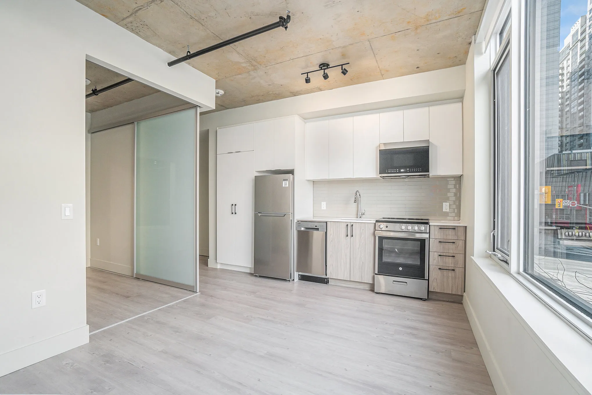Modern urban kitchen with sleek stainless steel appliances, minimalist cabinetry, and expansive windows offering a city view.