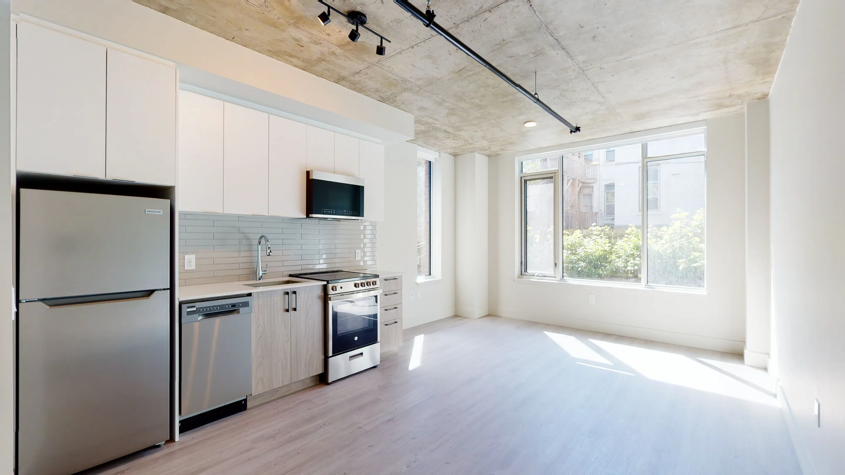 Bright, modern kitchen with stainless steel appliances, large window, and sleek cabinetry offering a stylish urban living space.