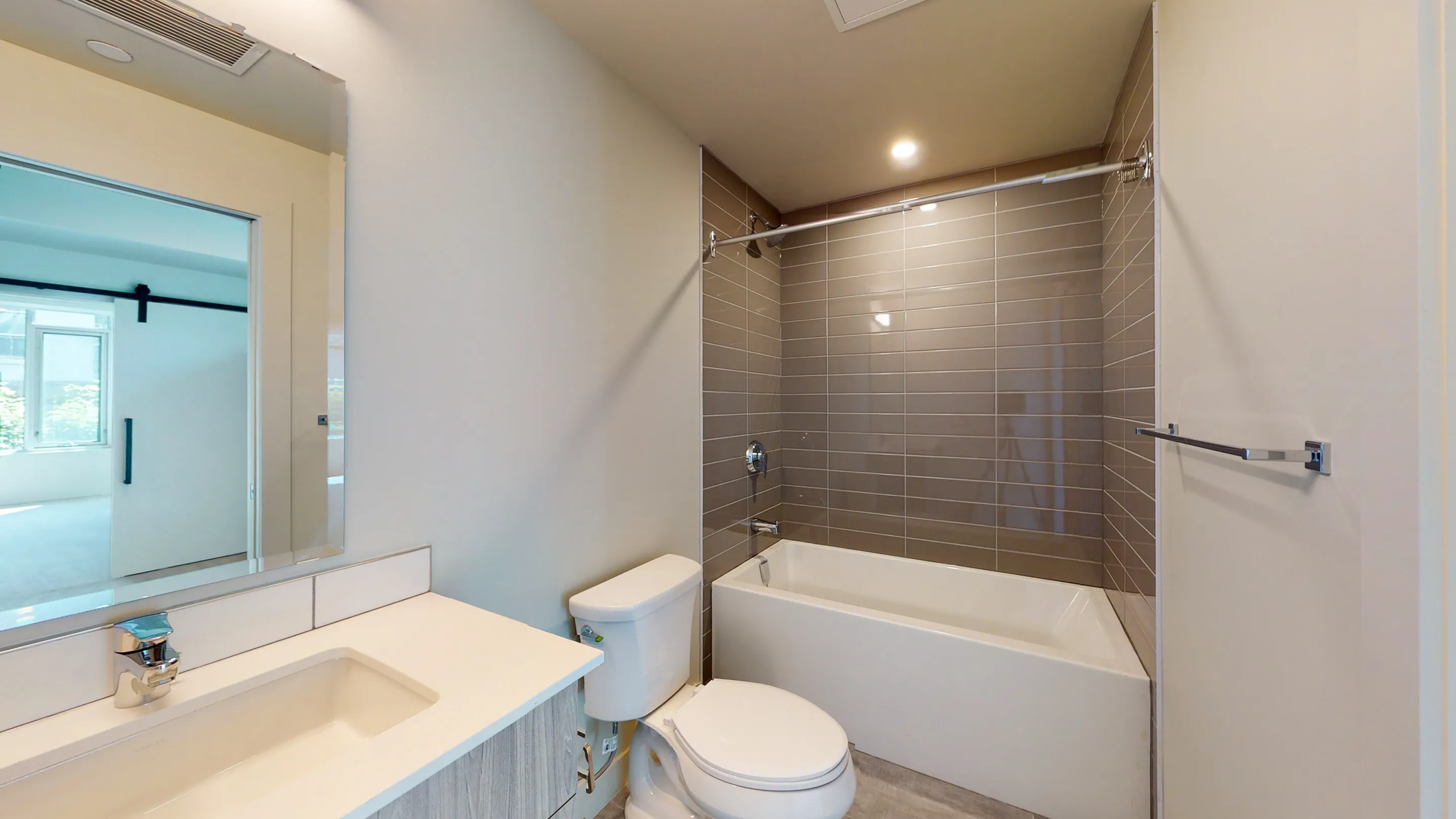 Modern bathroom with sleek tiled walls, a spacious bathtub, and a contemporary vanity, exuding a clean and bright atmosphere.