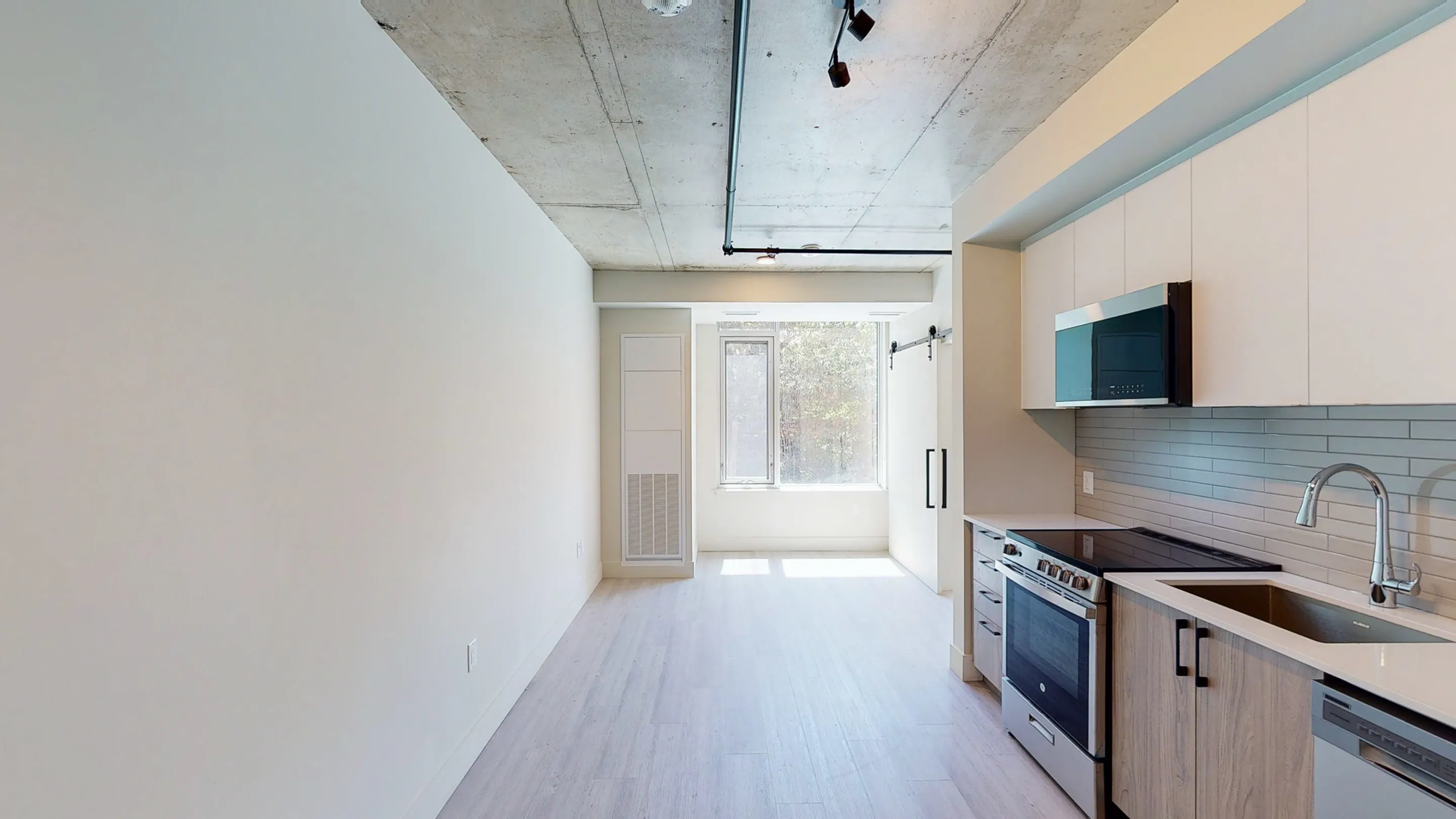 Bright and modern kitchen space featuring sleek appliances, elegant cabinetry, and large window for natural light.