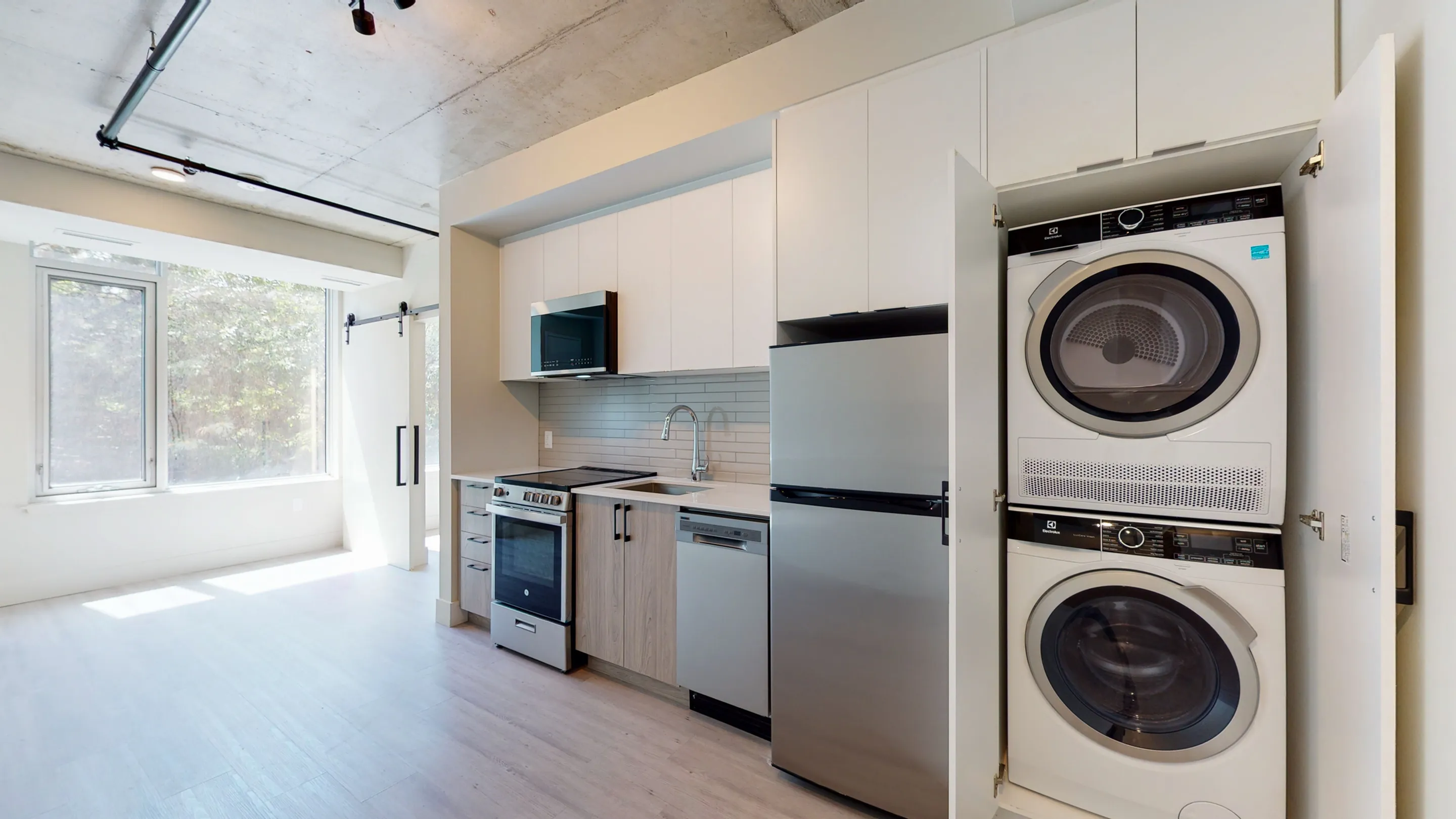 Modern kitchen with stainless steel appliances, in-unit washer and dryer, and large windows for natural light.