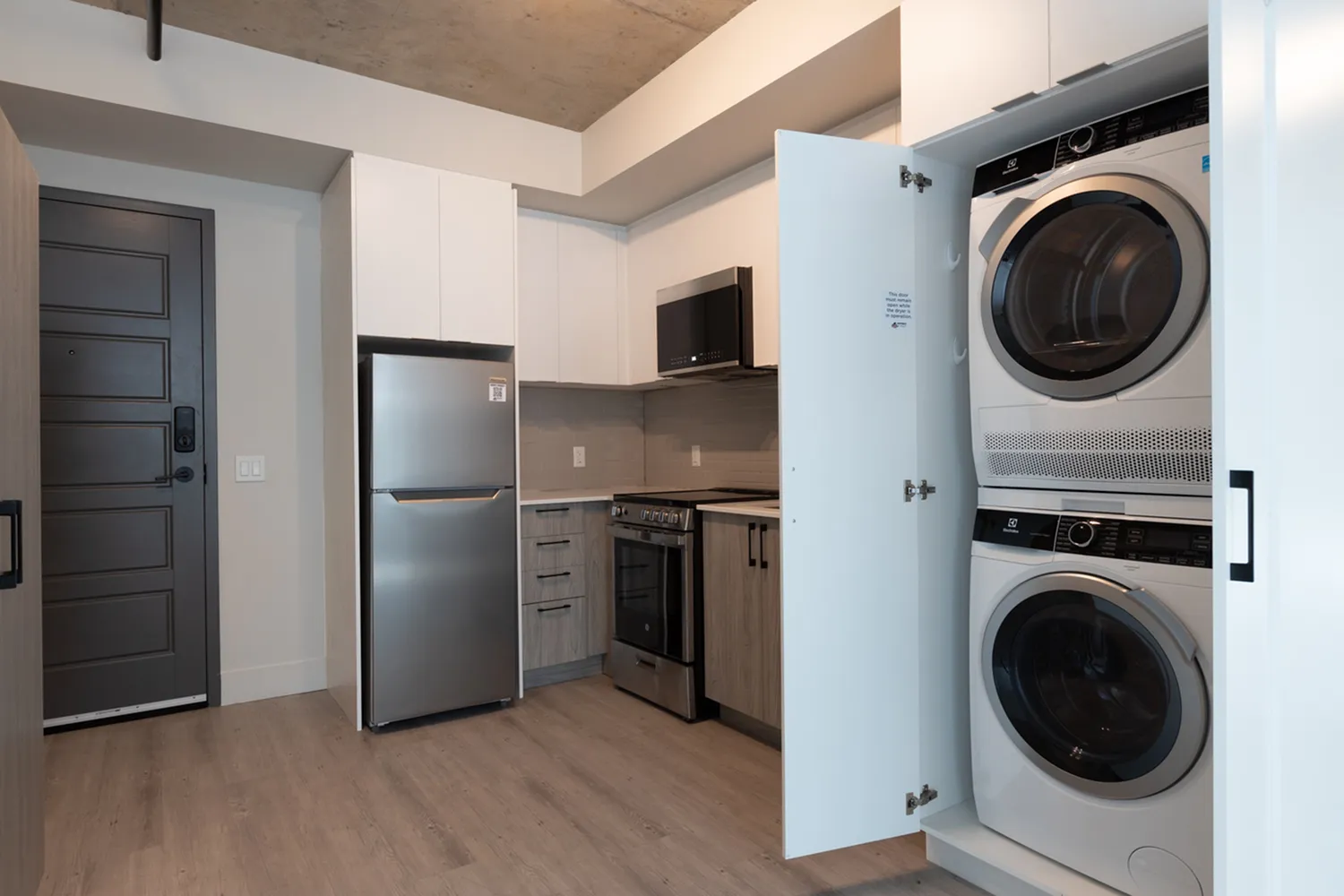 Modern kitchen with sleek stainless steel appliances and hidden laundry closet featuring a stacked washer and dryer.
