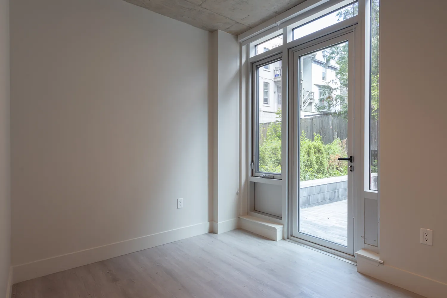 Bright interior with large glass doors leading to a private patio, featuring elegant flooring and a modern aesthetic.