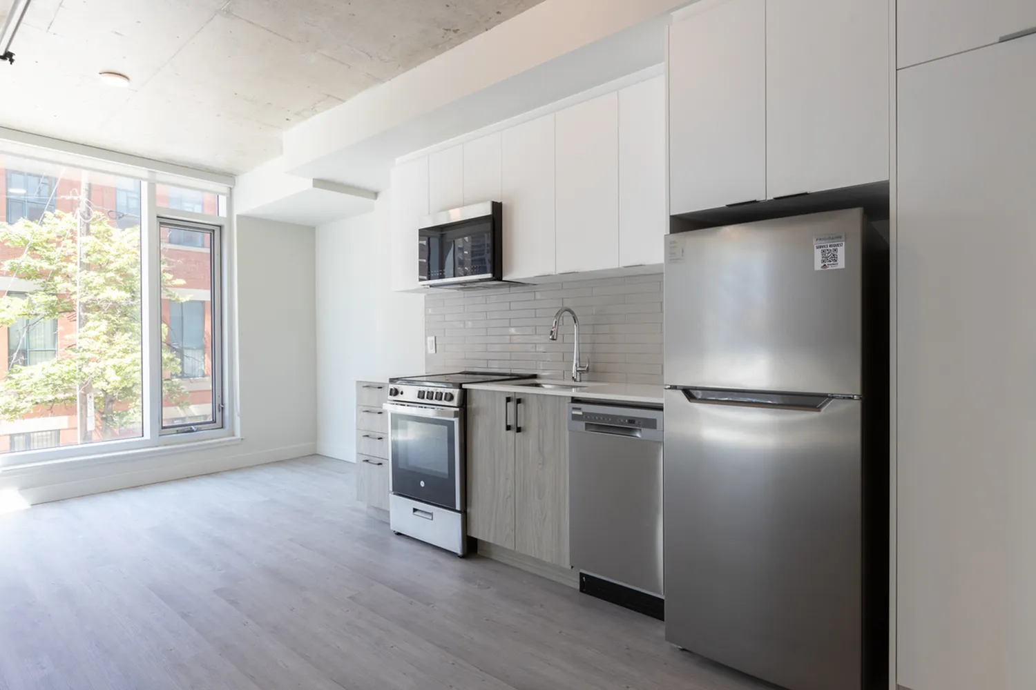 Bright, modern kitchen with stainless steel appliances, sleek cabinetry, and large windows offering natural light.