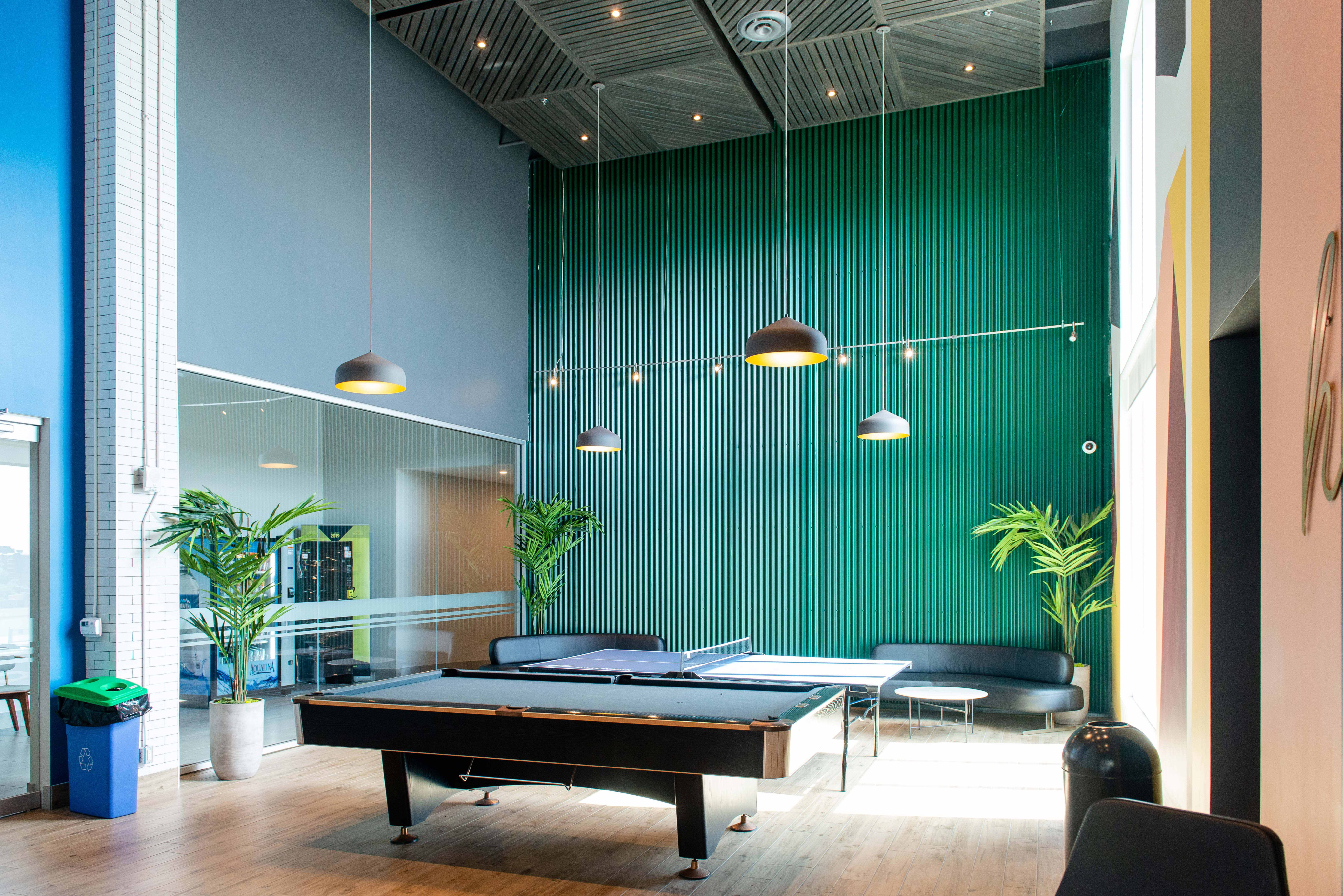 Stylish recreation lounge featuring a pool table, modern lighting, and lush plants.