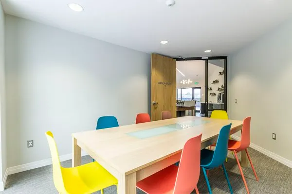 Modern conference room with a sleek wooden table surrounded by vibrant, colorful chairs, promoting a creative and inviting workspace.