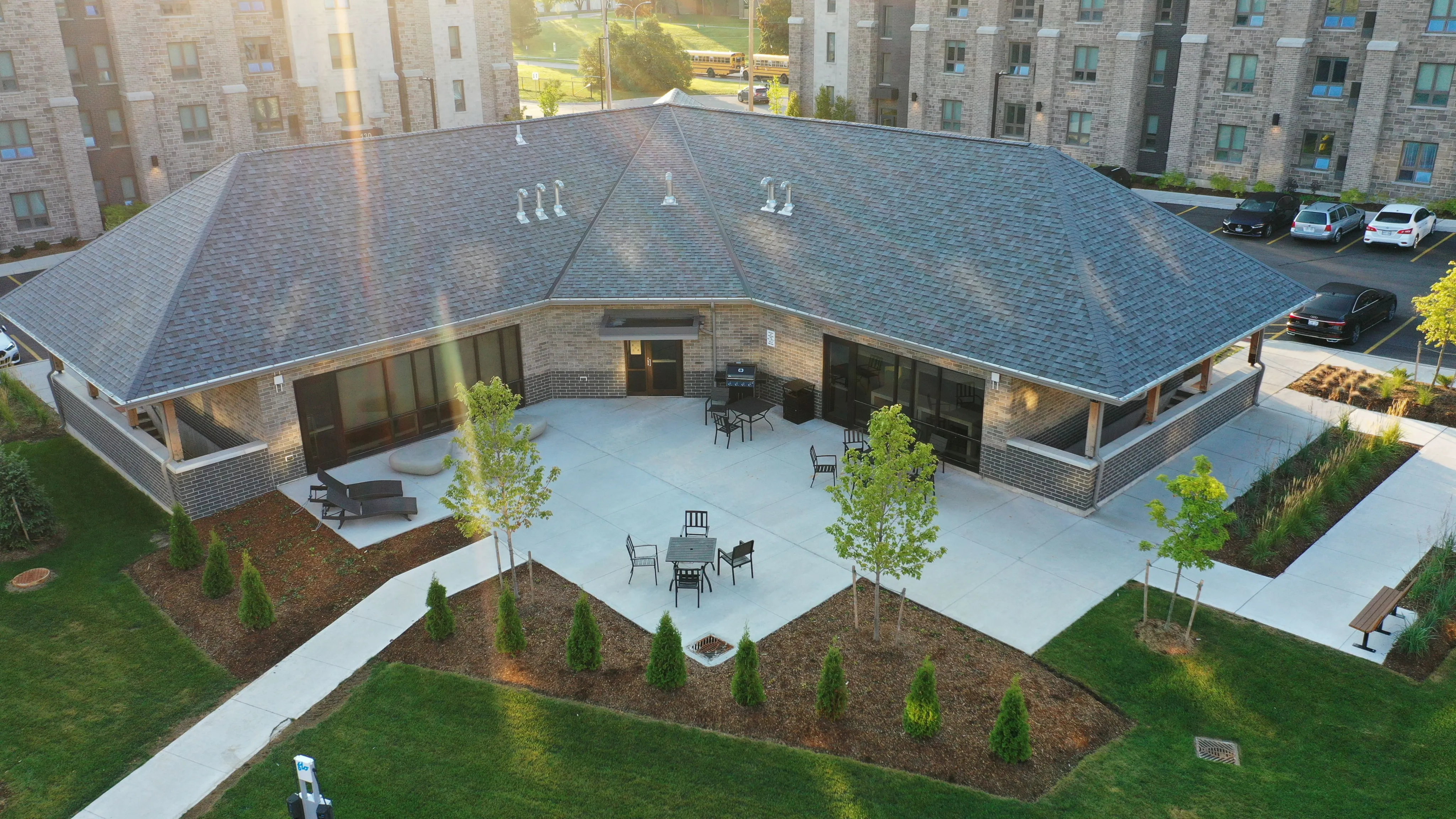 Elegant aerial view of a modern building with a spacious communal courtyard, seating areas, and lush greenery, perfect for relaxation and social gatherings.