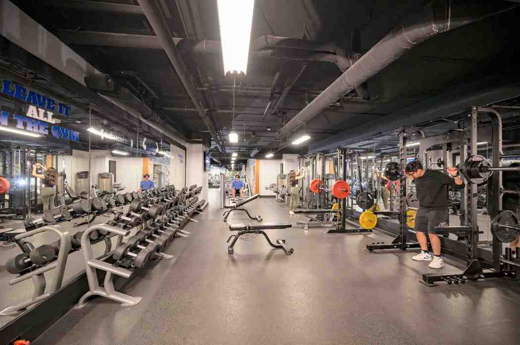 Modern fitness center featuring a variety of exercise equipment, free weights, and spacious workout areas.