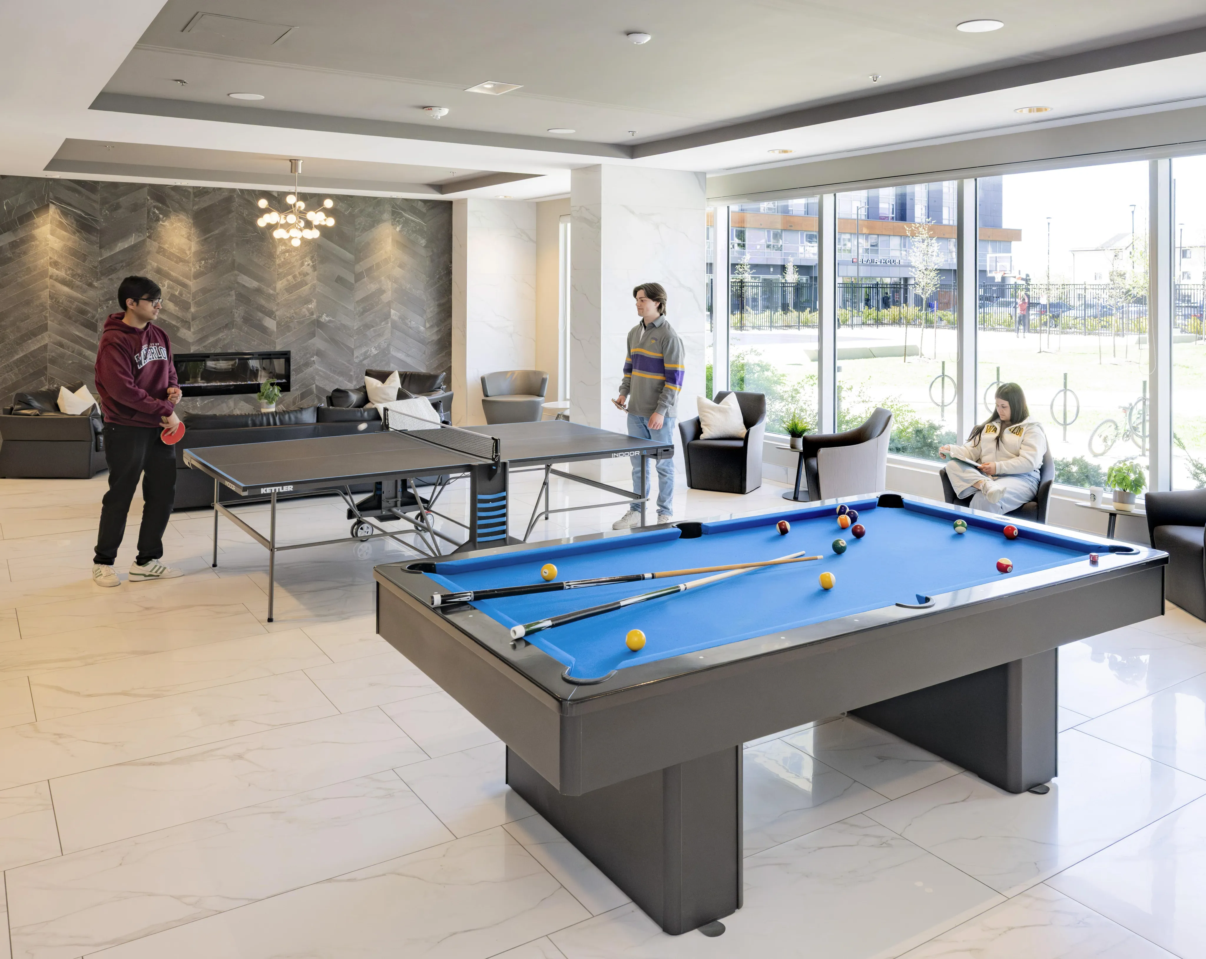 Spacious and stylish community lounge featuring a pool table, ping pong, and cozy seating with ample natural light.