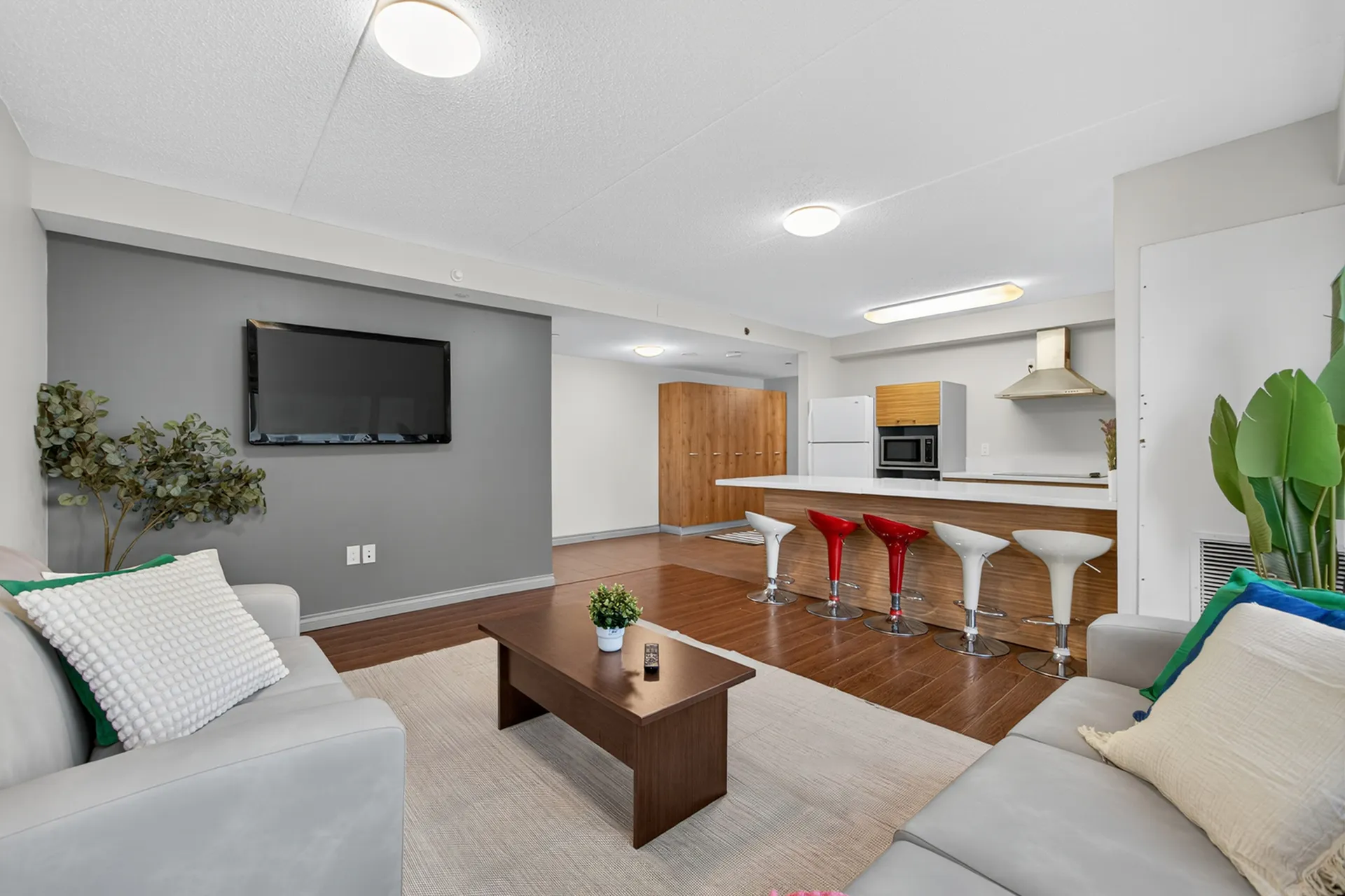 Modern open-concept living room with sleek kitchen, stylish bar seating, and elegant decor.