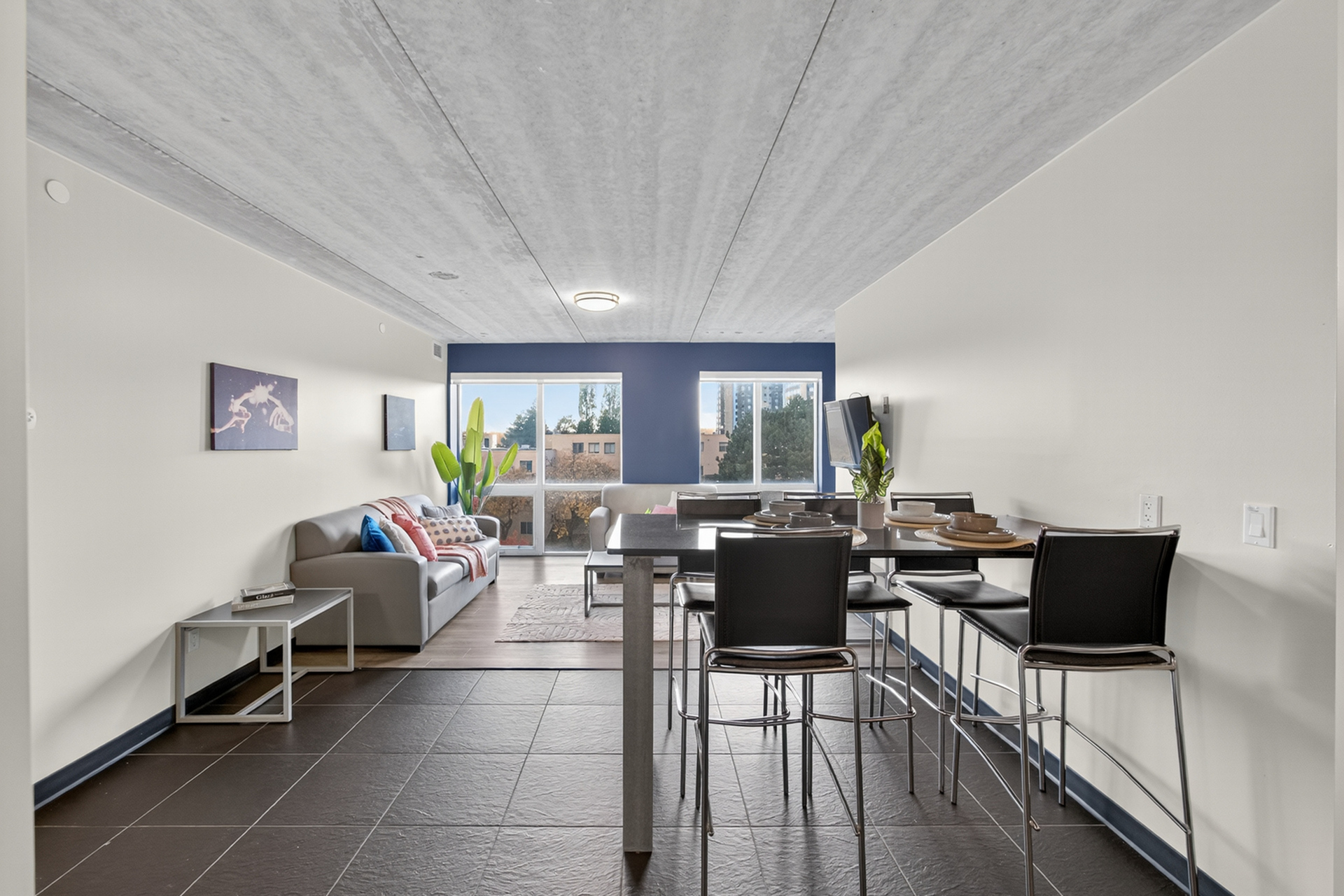 Bright open-concept apartment showcasing a modern living area with chic furniture, elegant dining space, and large windows offering stunning city views.