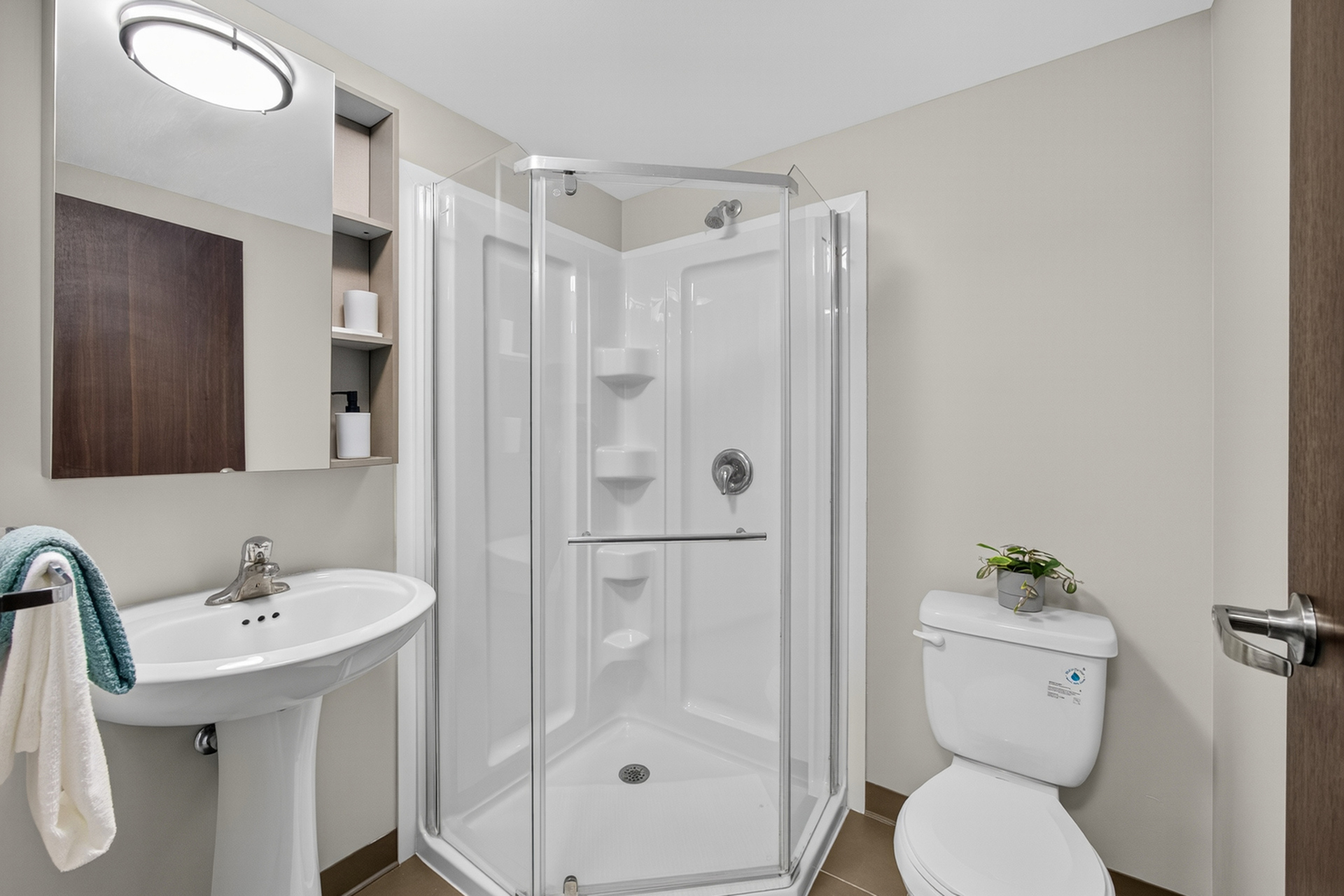 Elegant bathroom showcasing a modern glass shower, sleek pedestal sink, and contemporary fixtures.