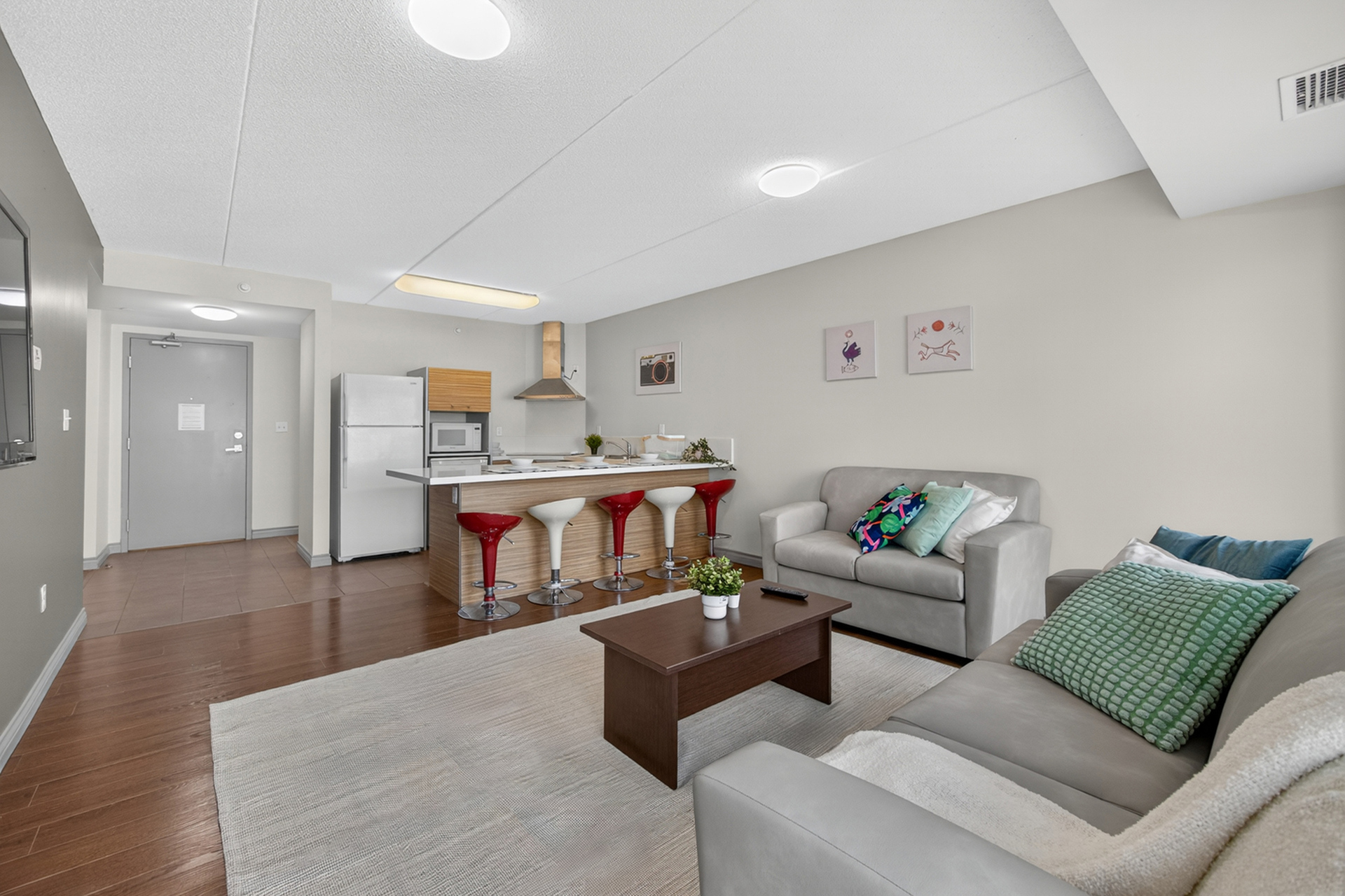 Modern open-concept living area with a sleek kitchen, stylish bar stools, and cozy seating, perfect for entertaining.