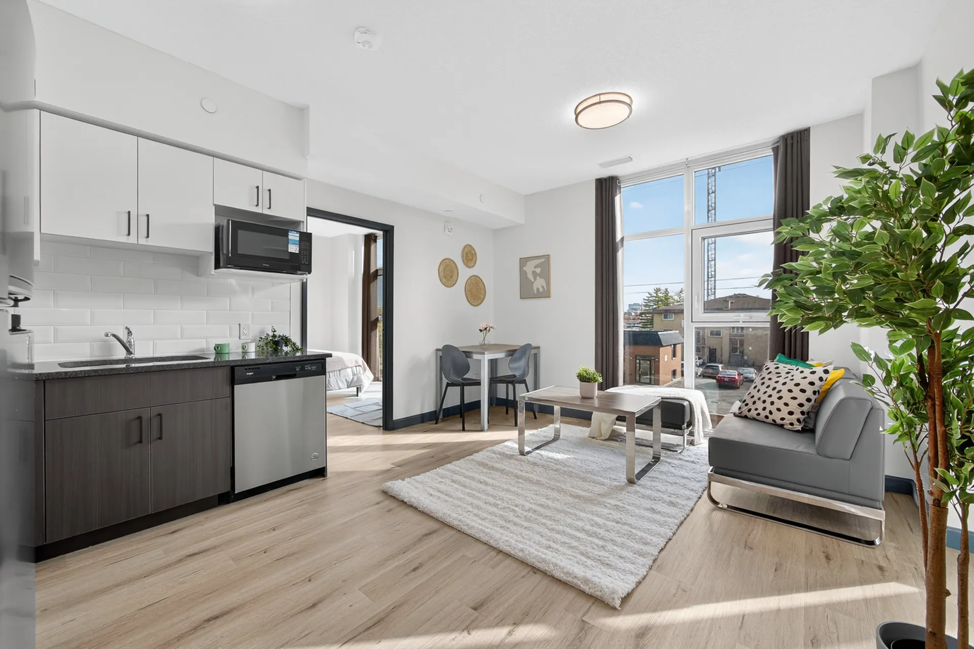 Bright and modern apartment with an open-concept kitchen and living area, featuring sleek cabinetry, large windows, and stylish decor.