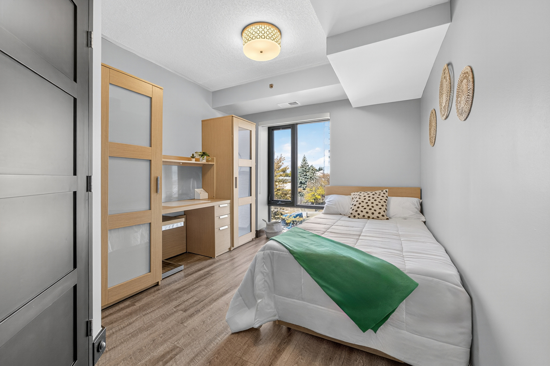 Bright and modern bedroom featuring a cozy bed, stylish wooden furniture, and a scenic window view, perfect for relaxation.