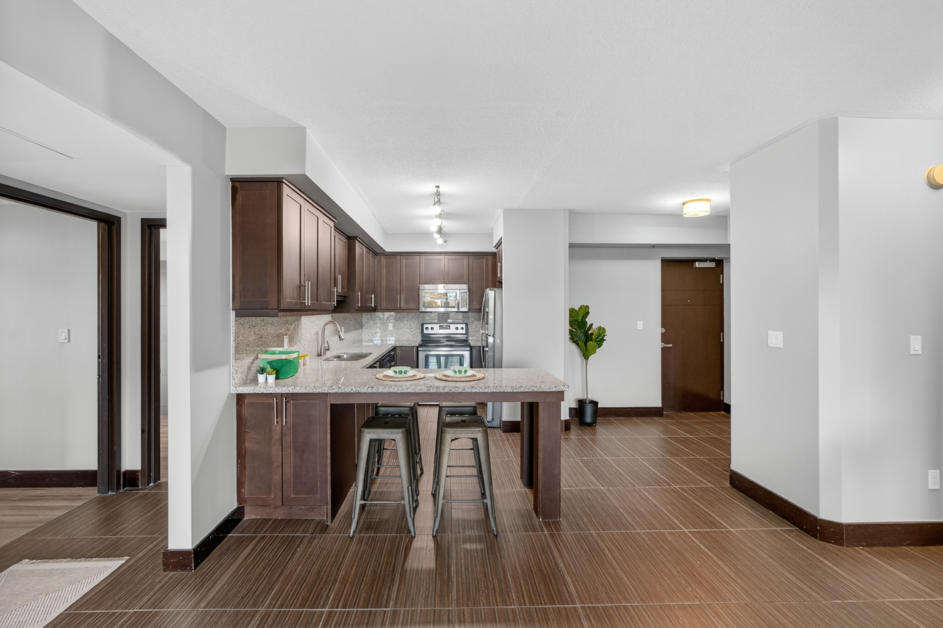 Chic modern kitchen with dark wooden cabinetry, sleek granite countertops, and stainless steel appliances, perfect for culinary enthusiasts.