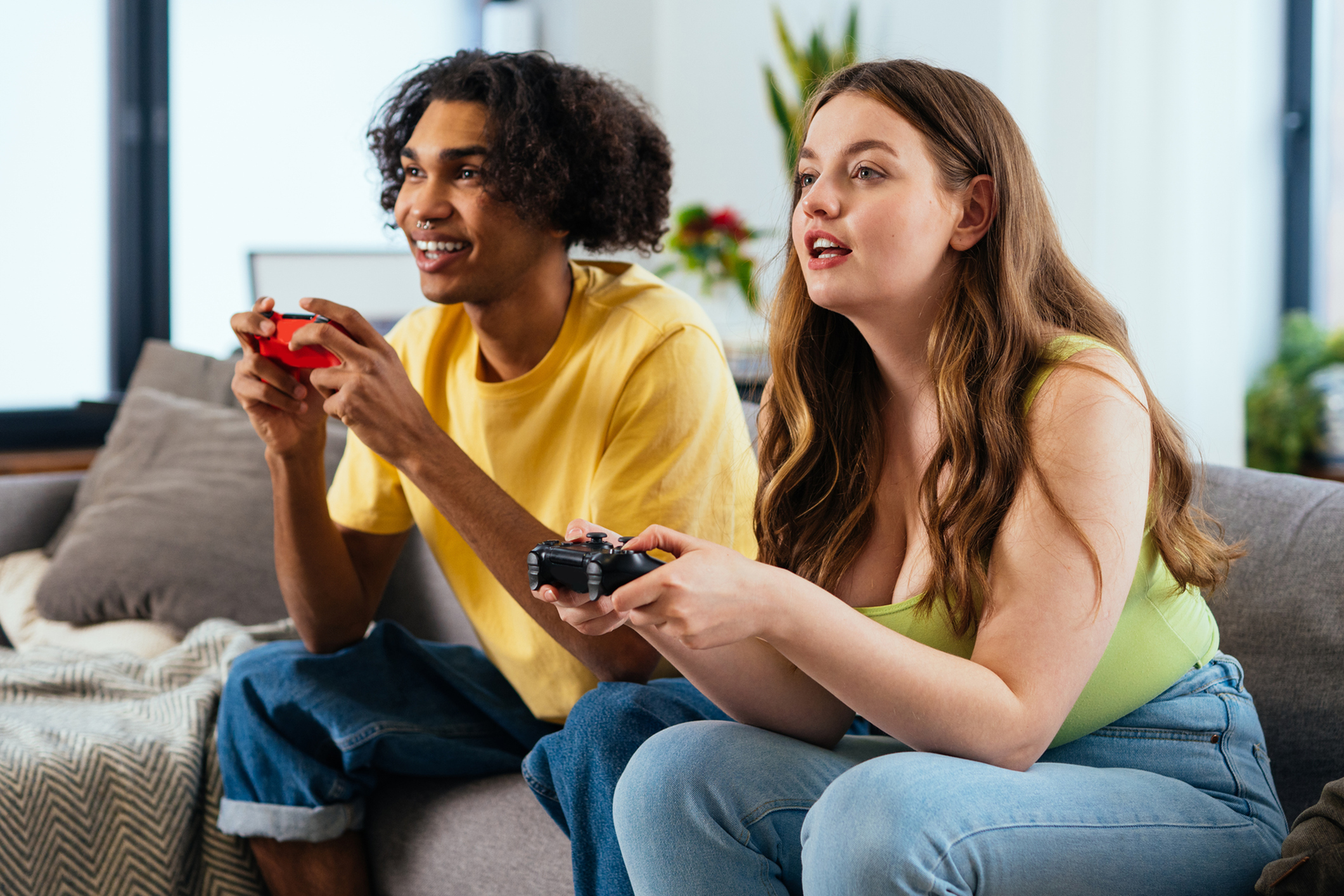 Two people enjoying video games on a cozy couch, showcasing a lively and inviting living room.
