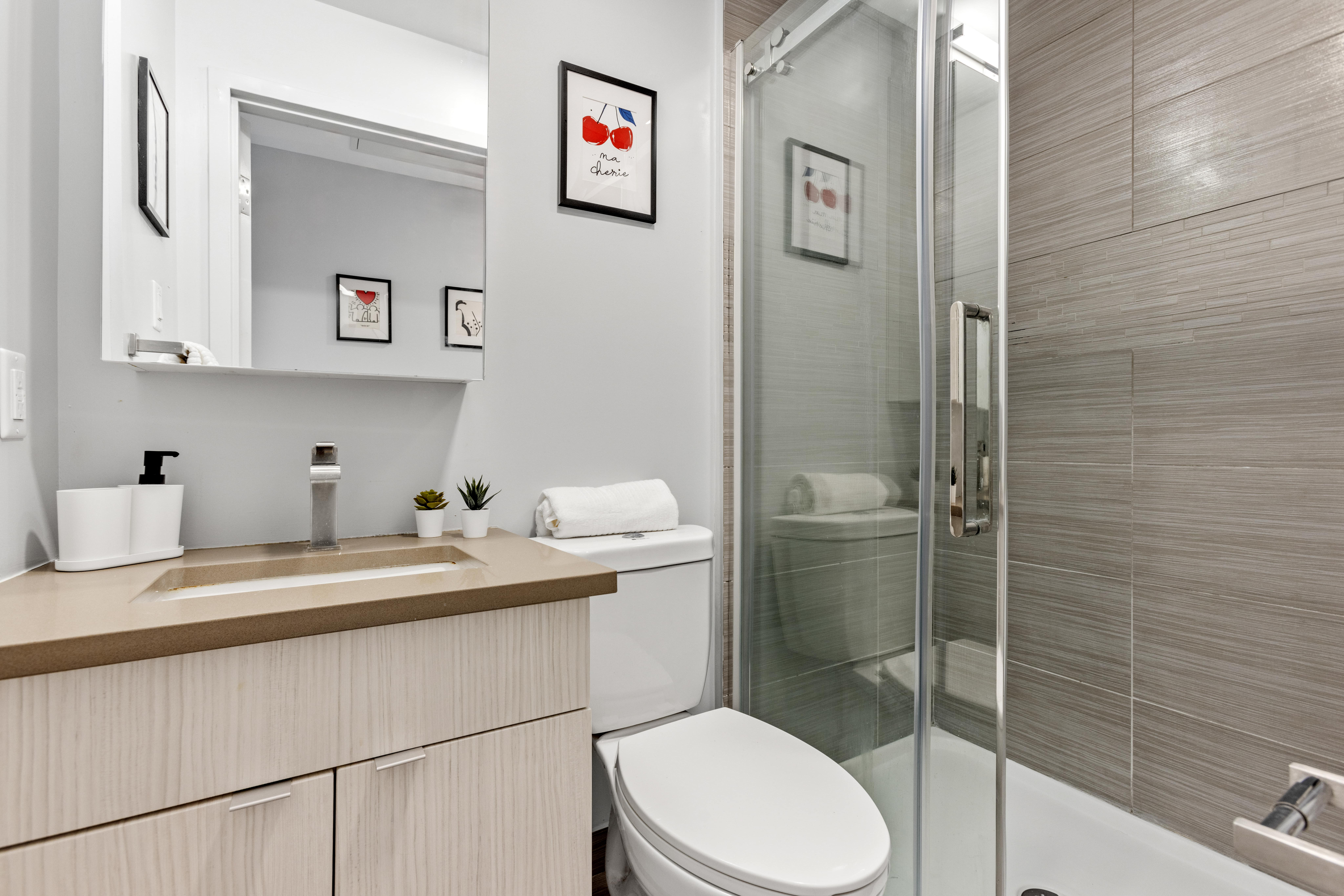 Modern bathroom showcasing a sleek glass shower, stylish vanity, and contemporary decor.