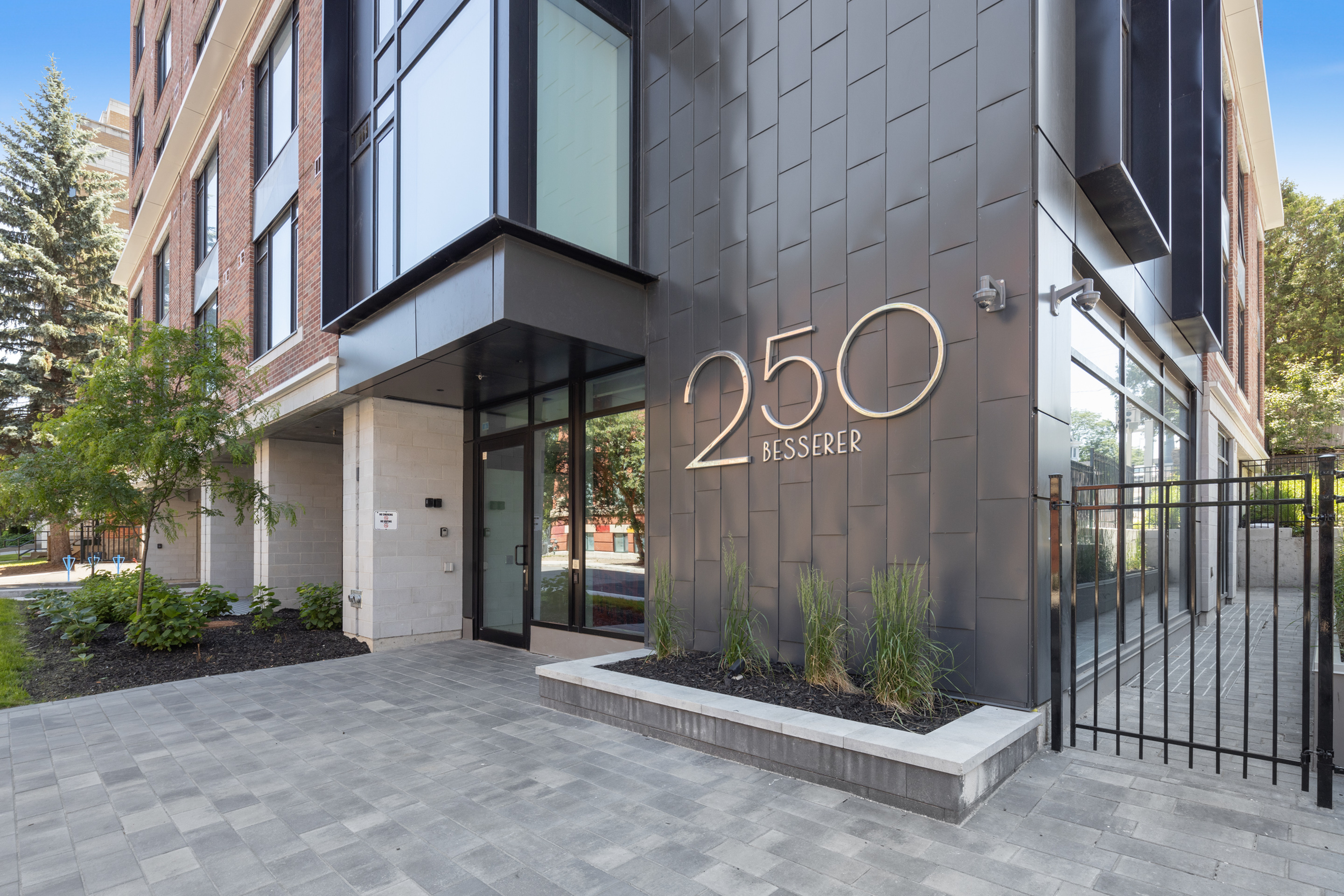 Modern apartment building entrance featuring sleek design and lush greenery at 250 Besserer.