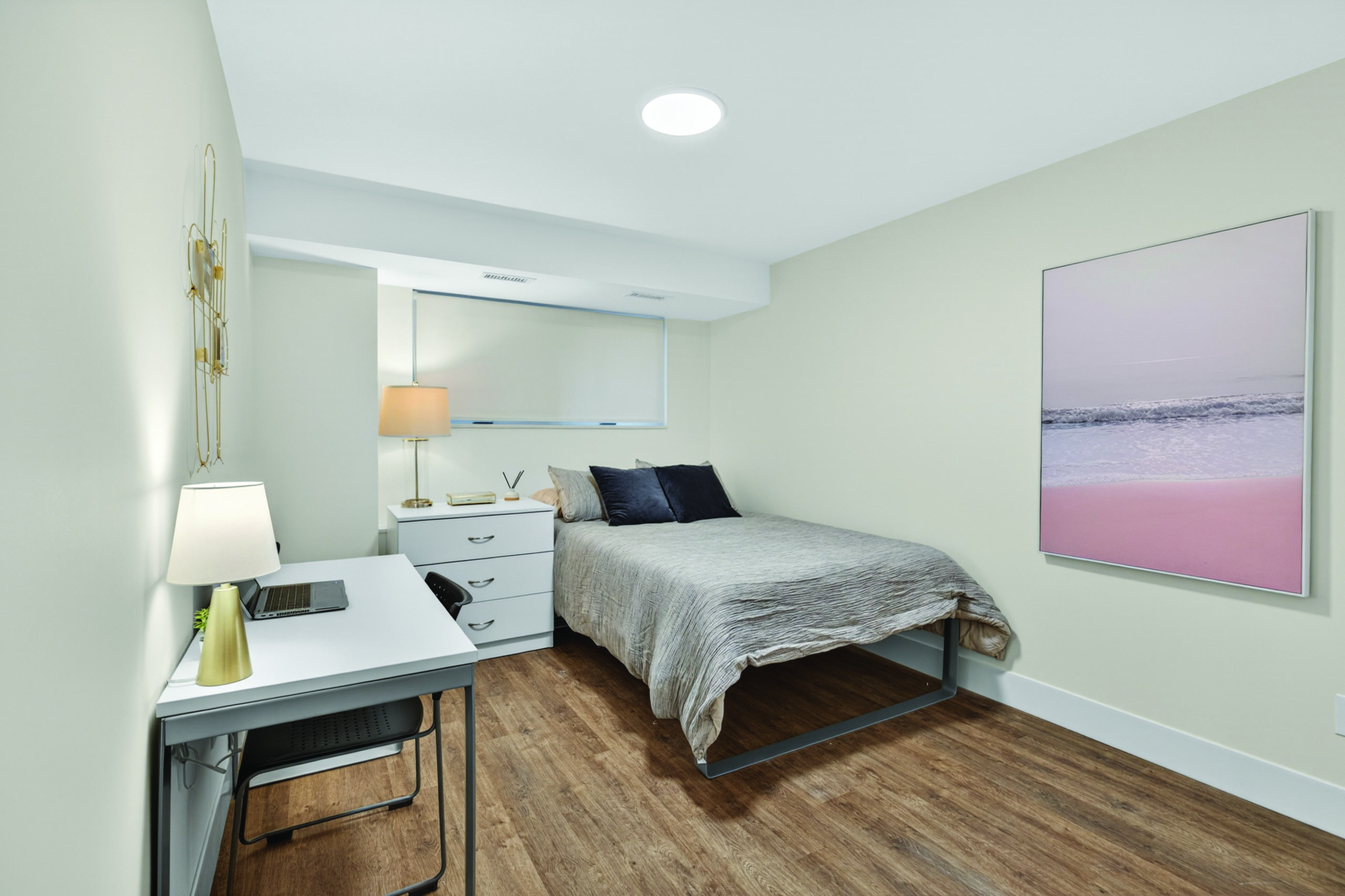 Cozy modern bedroom with stylish decor, featuring a comfortable bed, sleek desk, and elegant lighting on a rich wood floor.