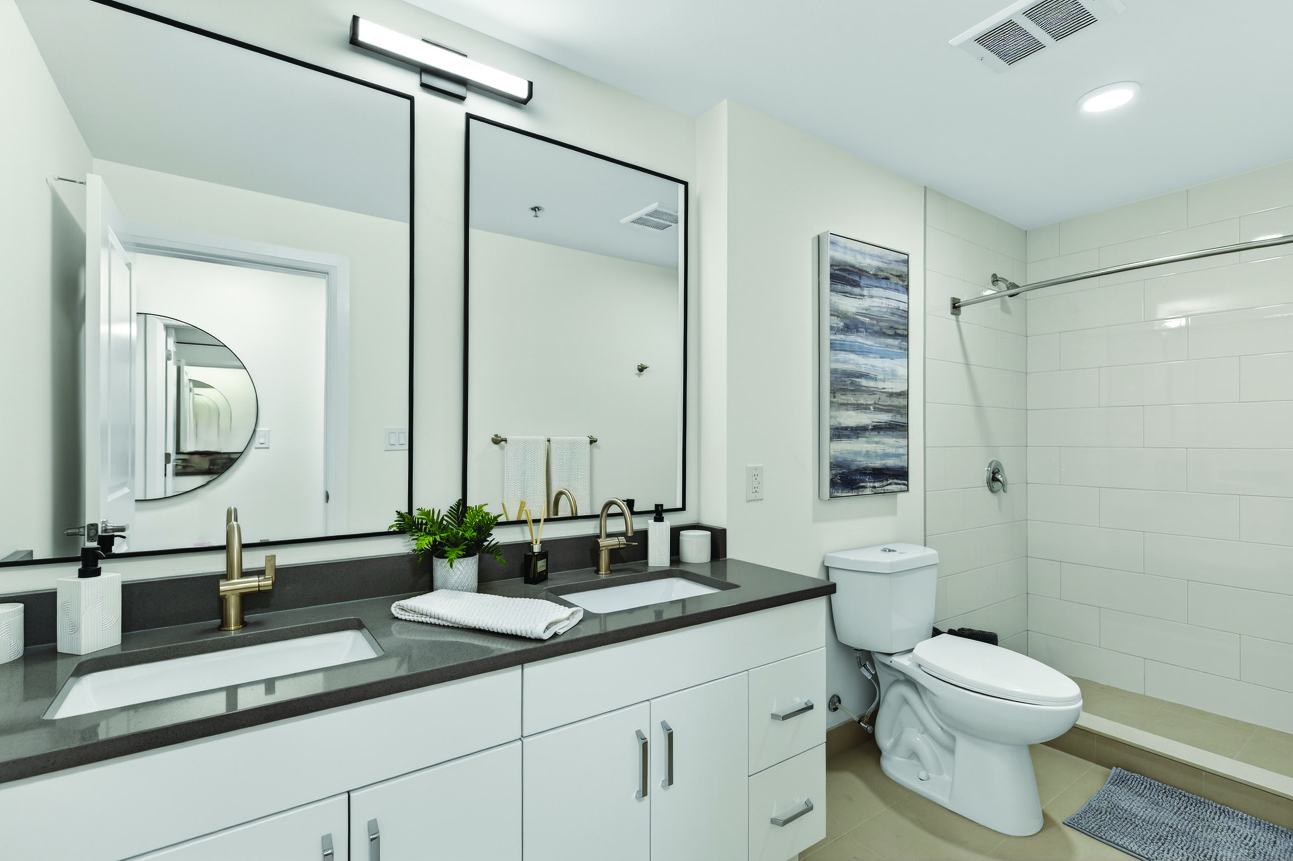 Elegant modern bathroom featuring dual vanities, sleek mirrors, and chic fixtures in a bright, sophisticated setting.
