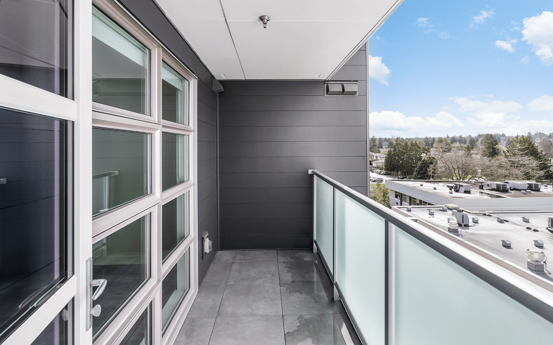 Contemporary balcony with sleek glass railing offering scenic views and ample natural light.