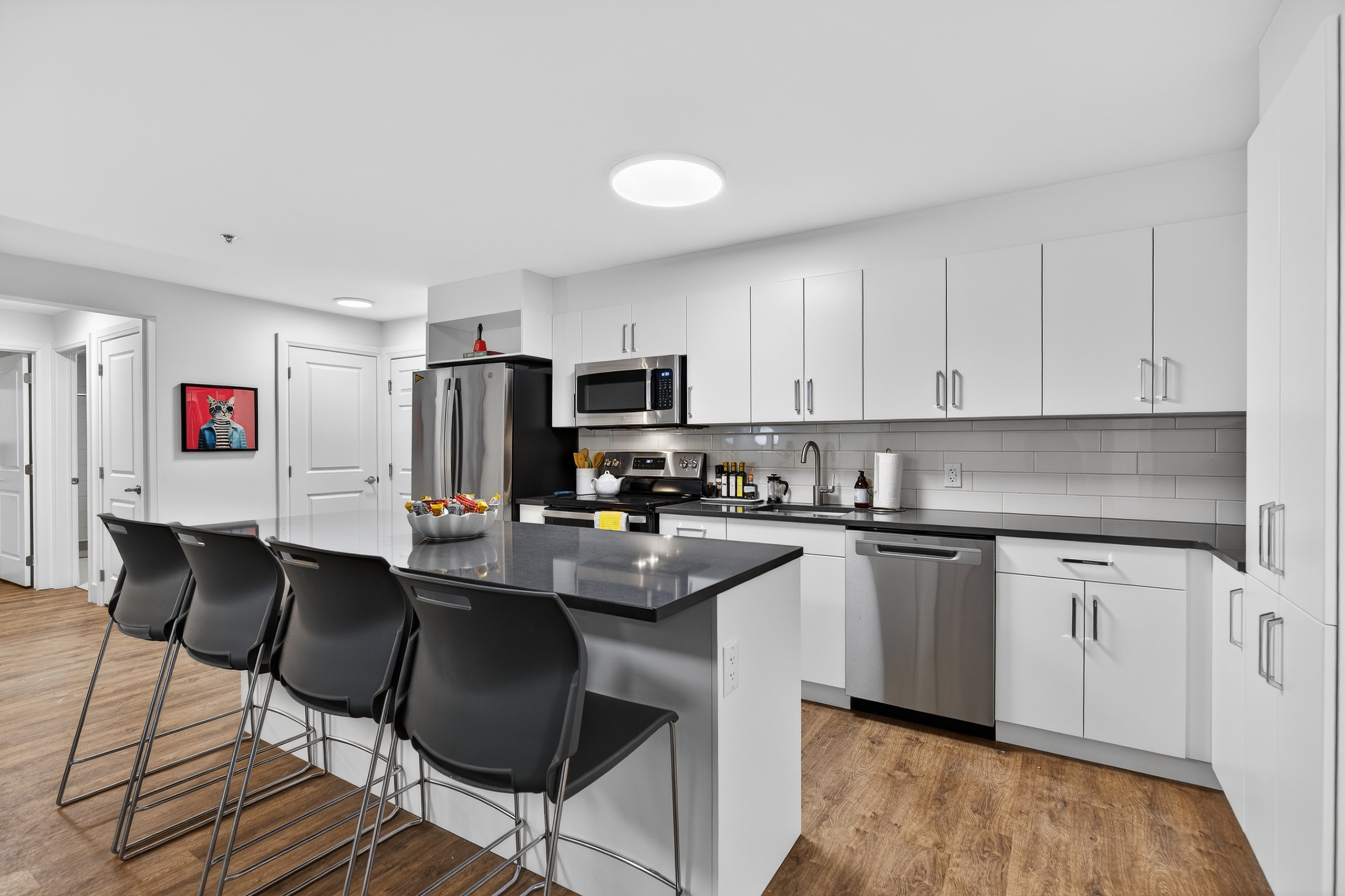 Modern kitchen with sleek white cabinetry, stainless steel appliances, and a spacious island counter with stylish bar stools.