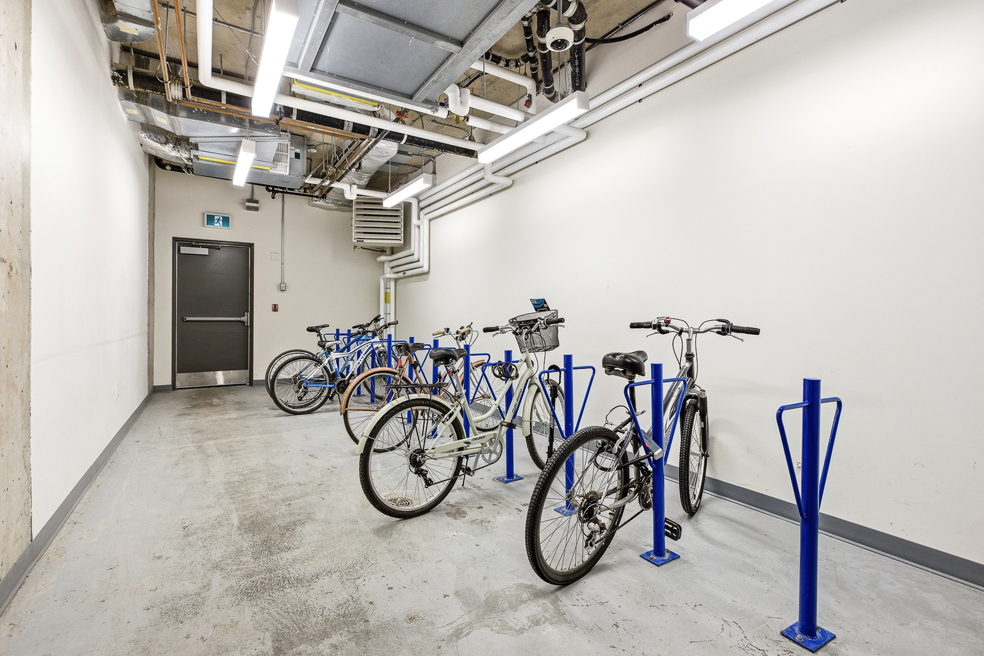 Secure and modern indoor bicycle storage area with multiple parking racks and conveniently placed under bright lighting.