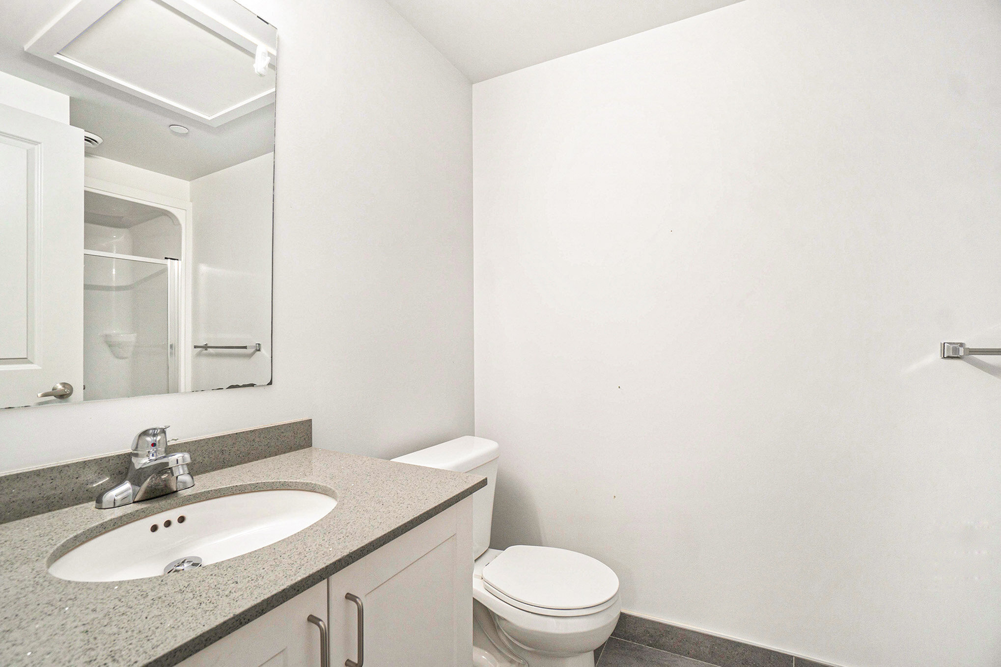 Bright and modern bathroom with sleek countertops and a spacious shower, offering a clean and contemporary design.