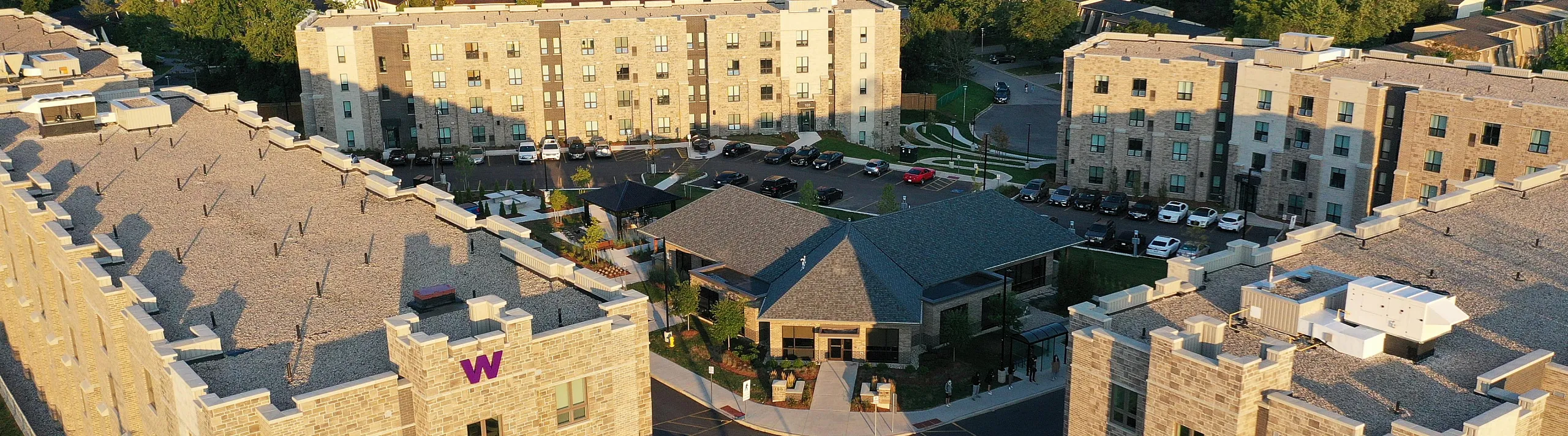 Charming apartment complex with modern architecture surrounded by lush greenery and ample parking, ideal for urban living.