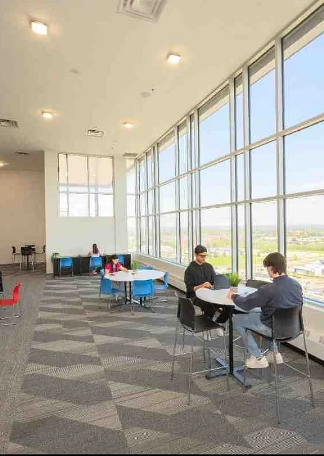 Bright and spacious meeting room with floor-to-ceiling windows offering stunning city views, modern seating, and plenty of natural light.