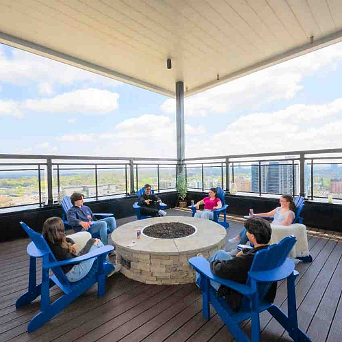 Inviting rooftop lounge featuring a cozy fire pit and stunning city views, perfect for social gatherings and relaxation.