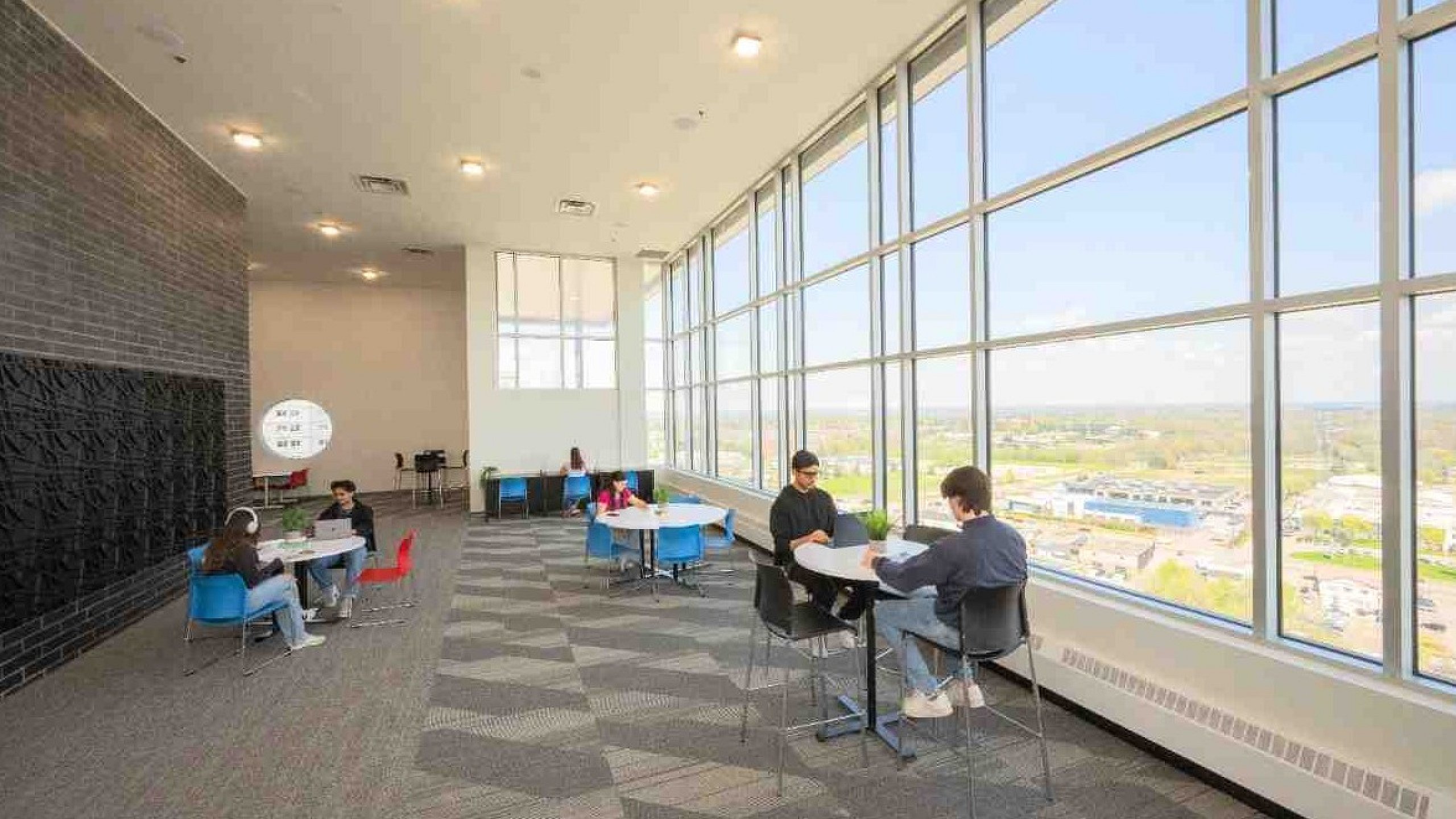 Bright and spacious seating area with floor-to-ceiling windows showcasing a stunning city view, perfect for relaxation and study.