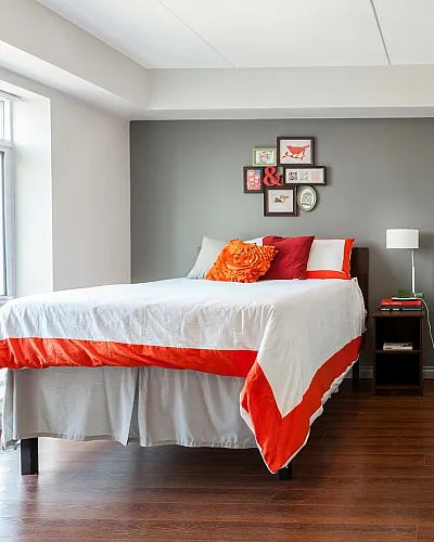 Bright and modern bedroom featuring a cozy bed with colorful pillows, elegant desk area, and stylish wall decor.