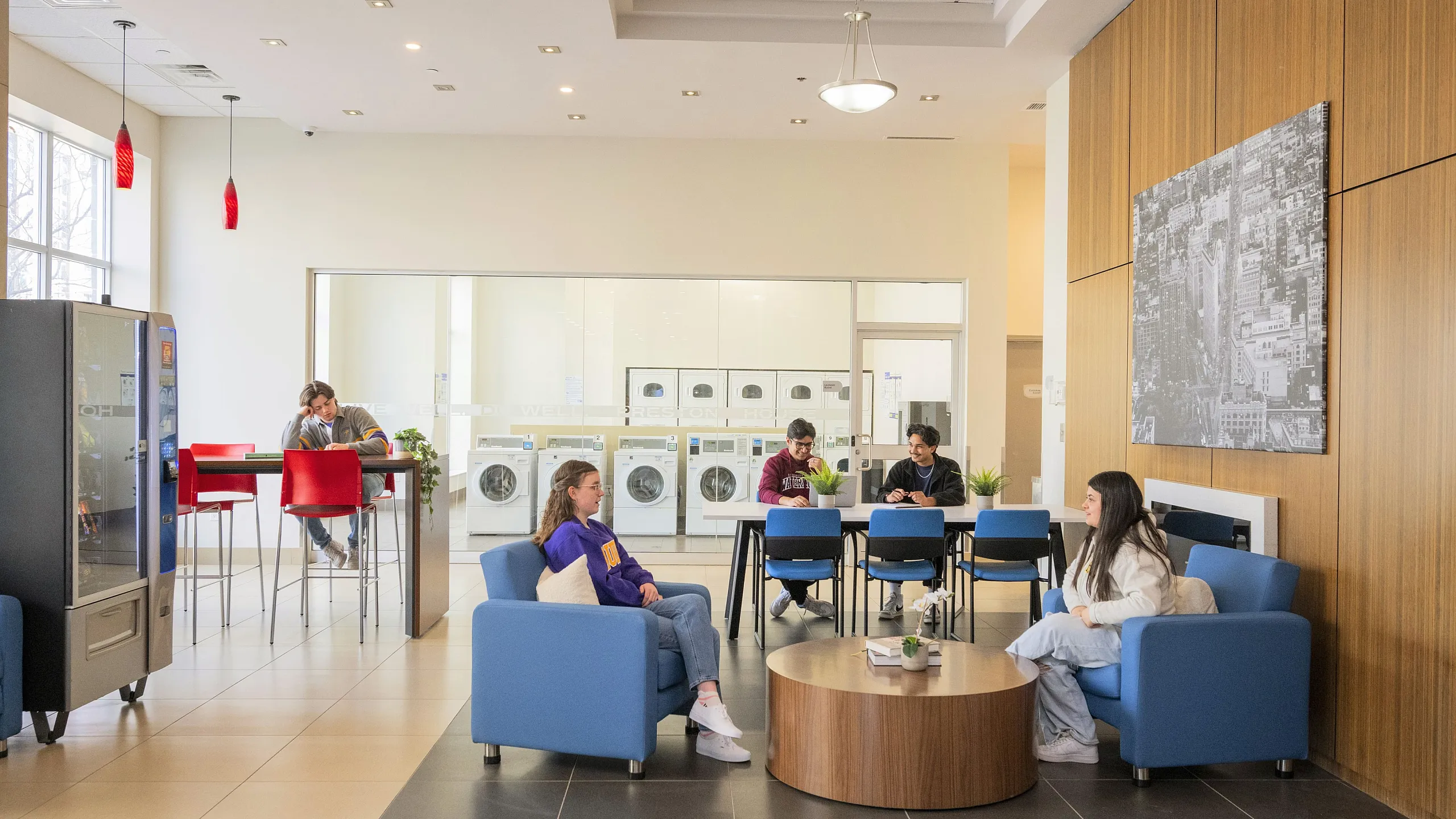 Modern communal area with vibrant seating and laundry facilities, featuring a cozy lounge, vending machines, and contemporary decor.