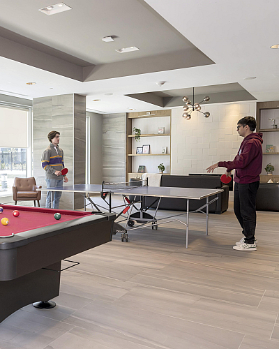 Modern recreational room with a sleek pool table, ping pong area, and cozy seating; perfect for entertainment and relaxation.