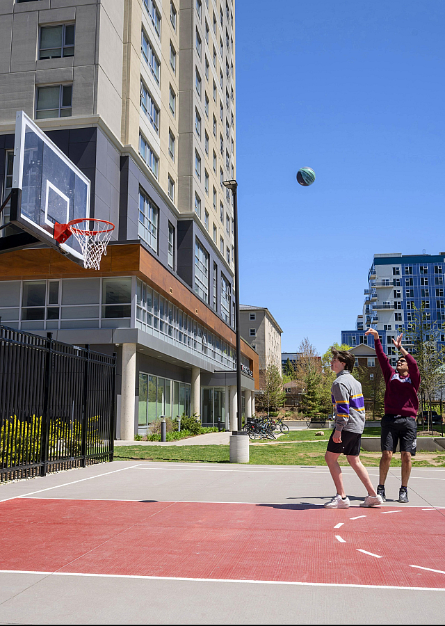 Inviting outdoor basketball court adjacent to modern apartment building, showcasing vibrant community sports amenity.