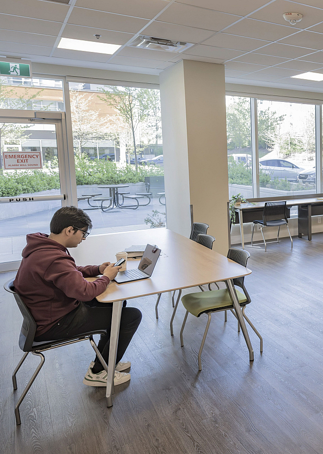 Spacious and bright community room with large windows, modern furniture, and a peaceful atmosphere ideal for studying or meetings.