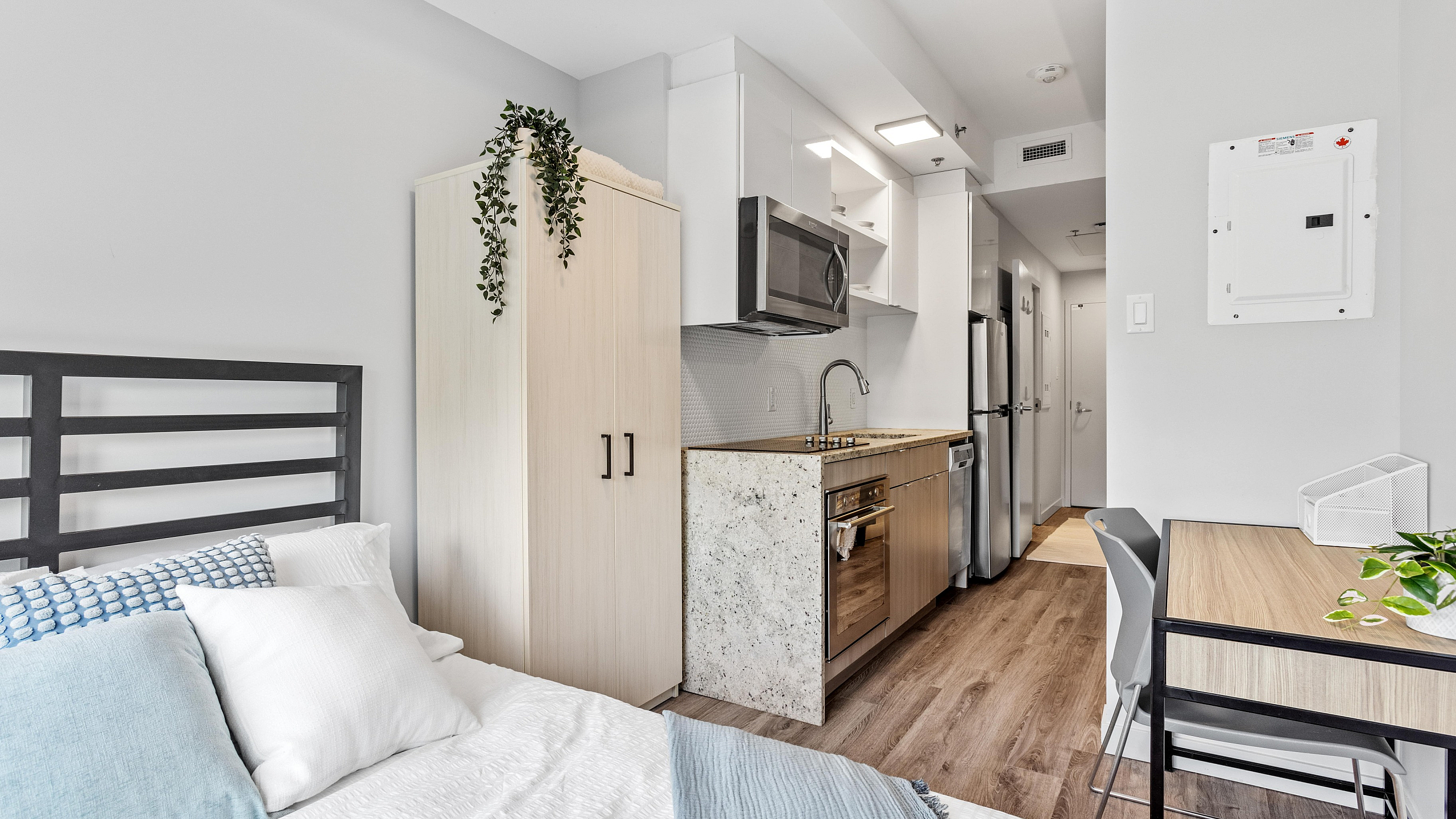Modern studio apartment with cozy bed, compact kitchen, and stylish workspace, perfect for urban living.